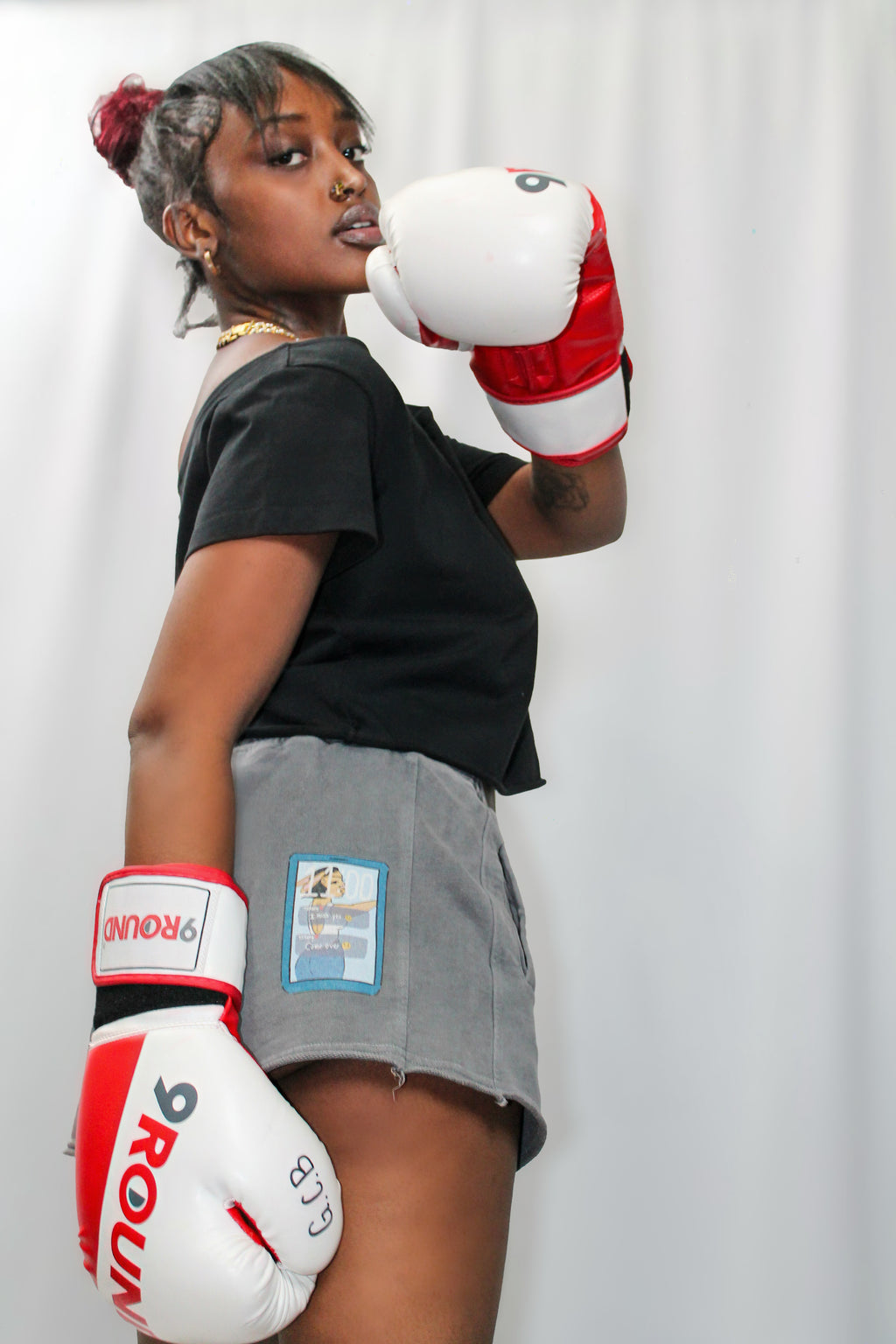 Person wearing boxing gloves and a skirt with a brand logo on a white background