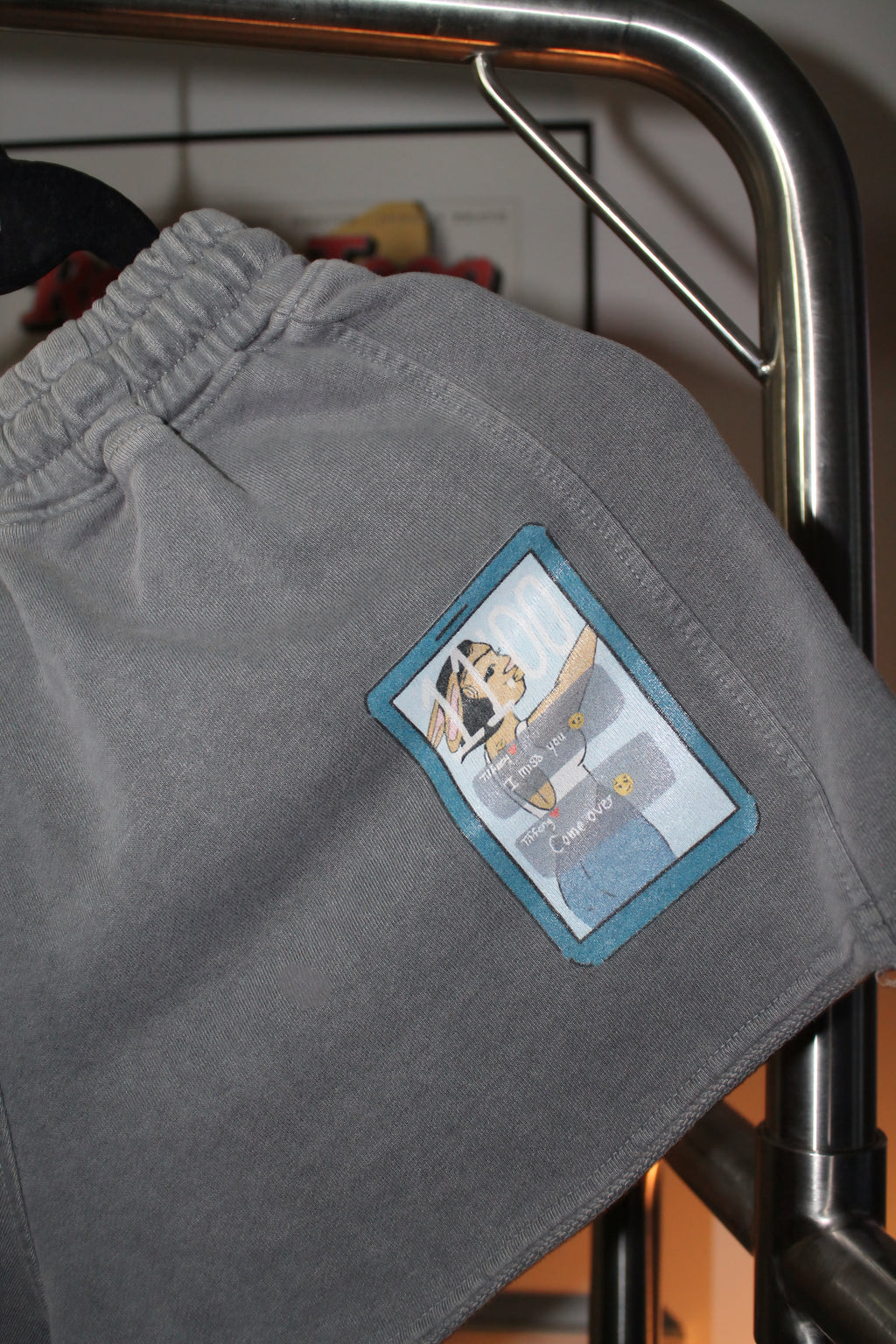 Gray shorts with a patch on a metal rack
