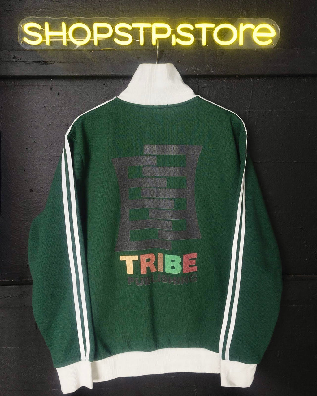 Green jacket with 'TRIBE' print on a dark background with neon sign