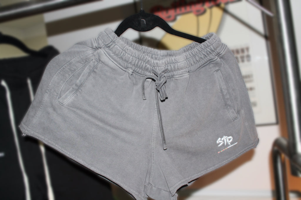 Gray shorts with a brand logo on a hanger against a blurred background