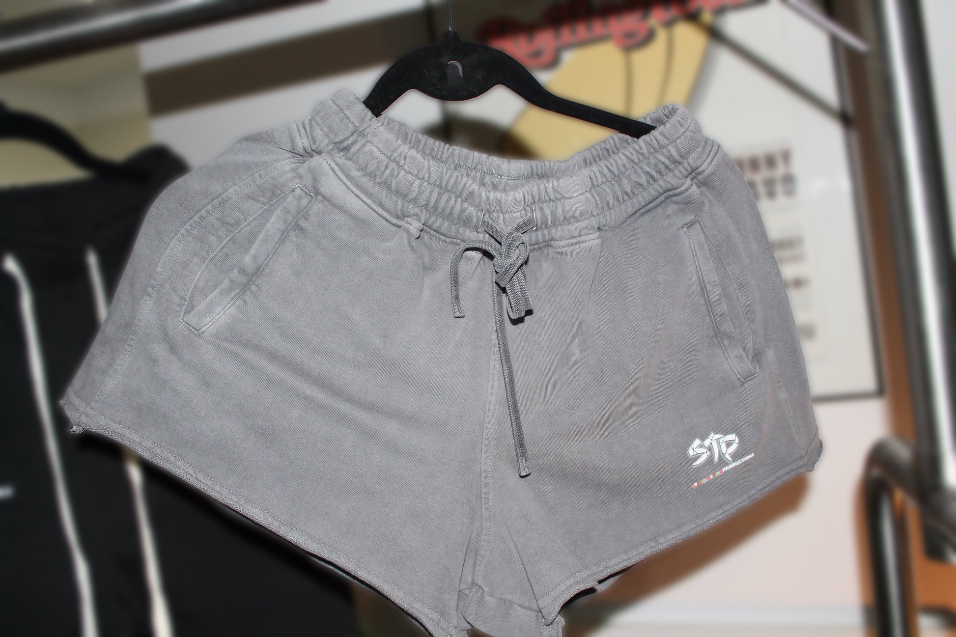 Gray shorts with a brand logo on a hanger against a blurred background