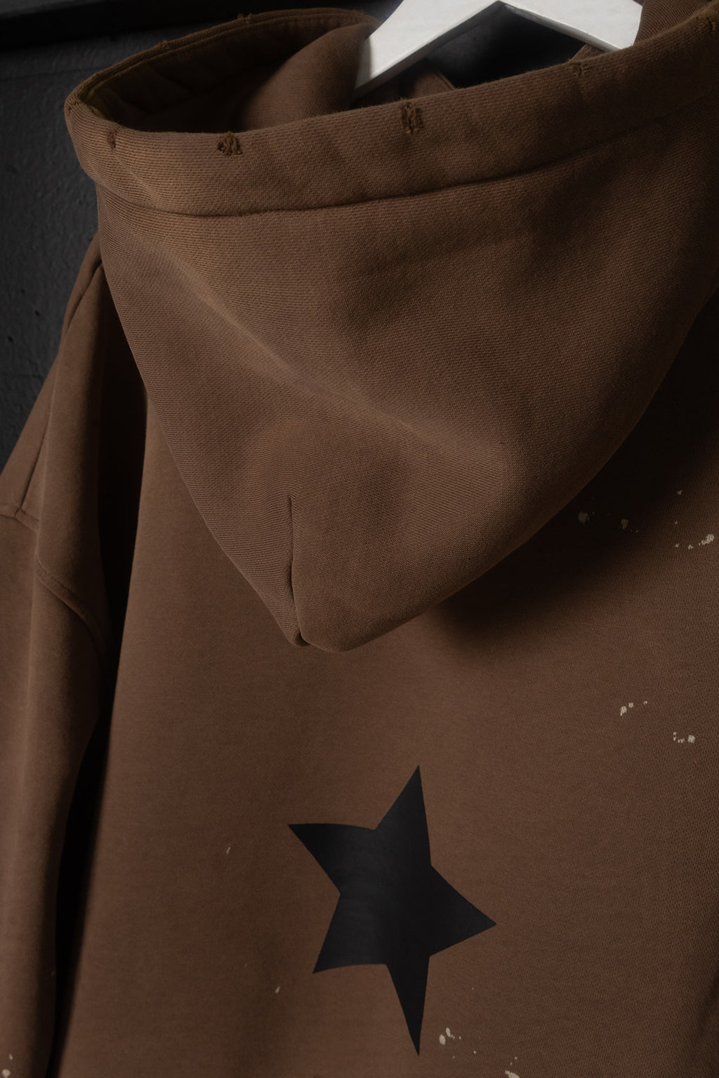 Brown hooded garment with a black star design on a dark background