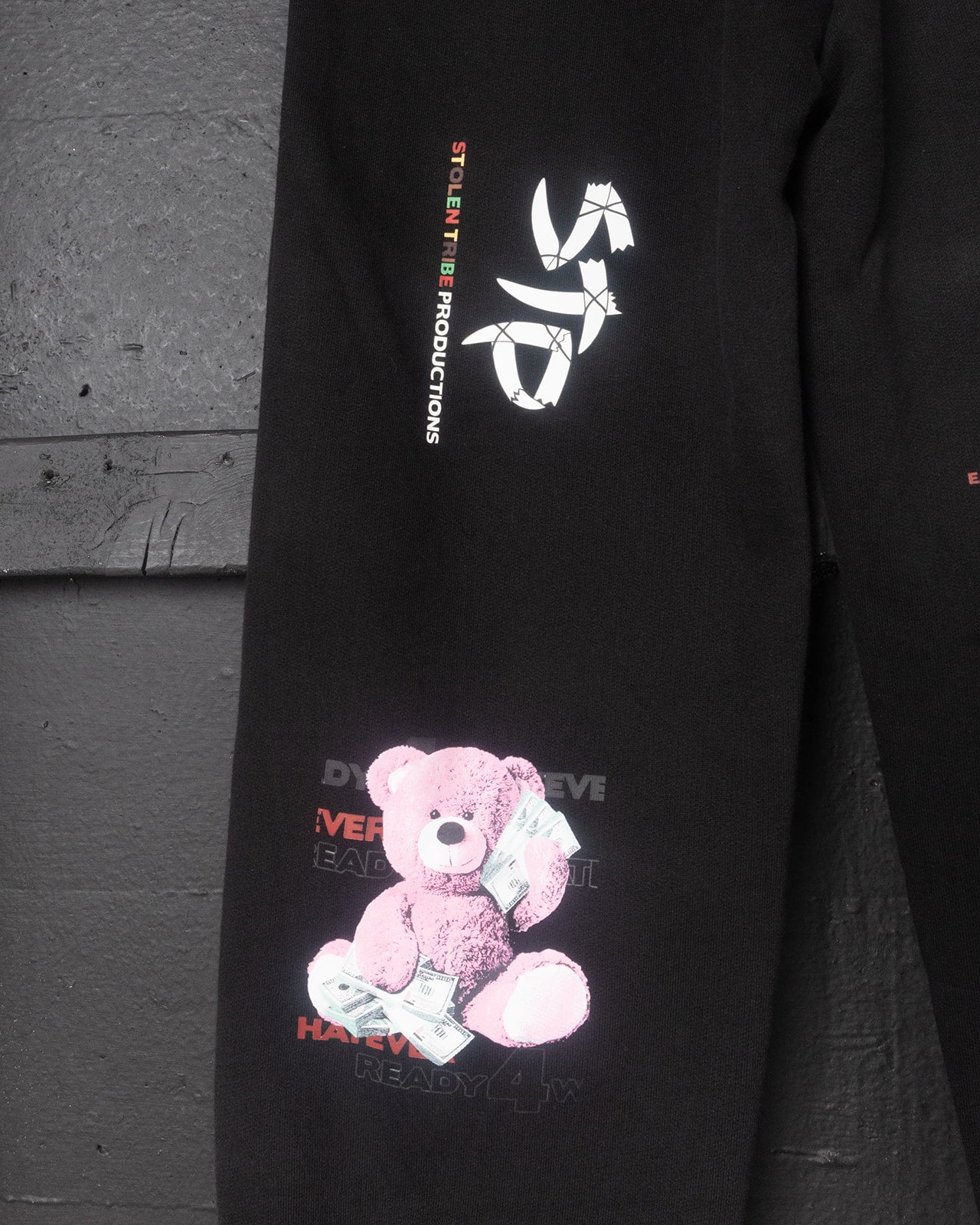Black sweatshirt with pink teddy bear graphic and text on a gray background