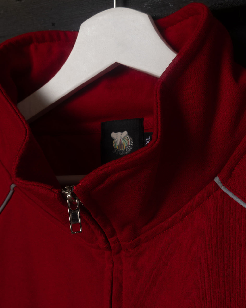 Red jacket with a brand logo on a hanger against a dark background