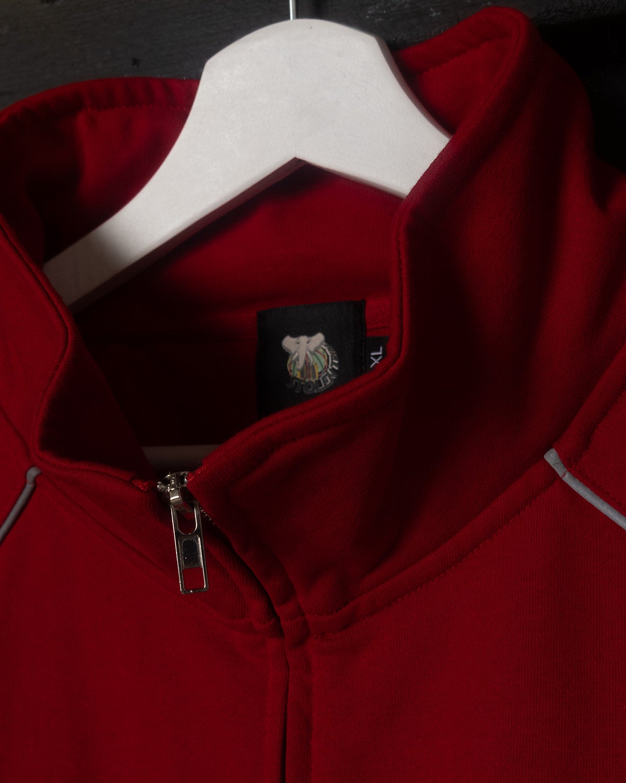 Red jacket with a brand logo on a hanger against a dark background