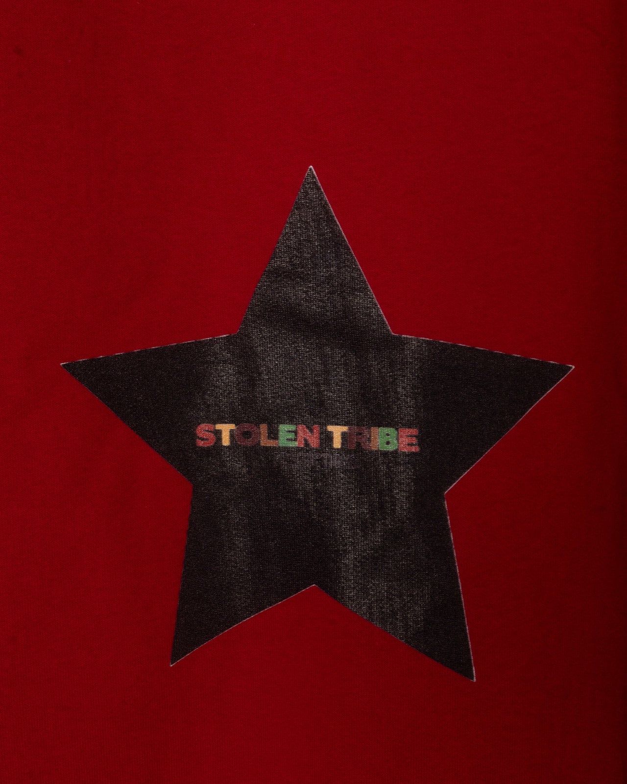Black star-shaped patch with 'STOLEN TRIBE' text on a red background