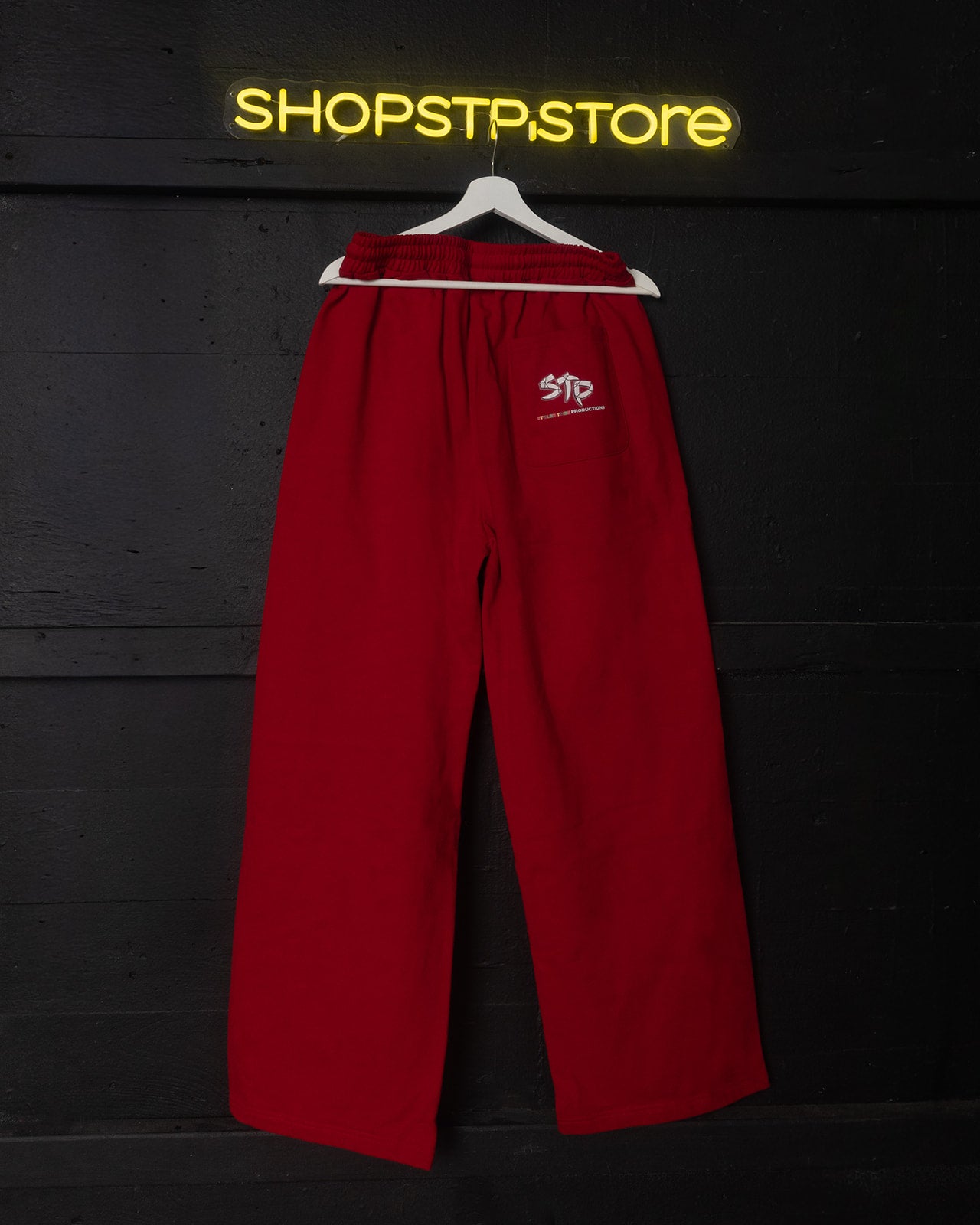 Red pants on a hanger with 'SHOPSTP STORE' sign in the background
