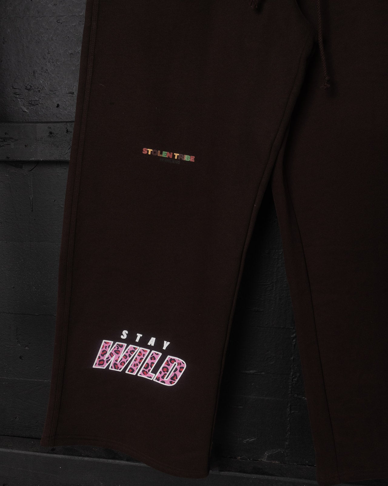 Dark brown pants with embroidered text on a dark background