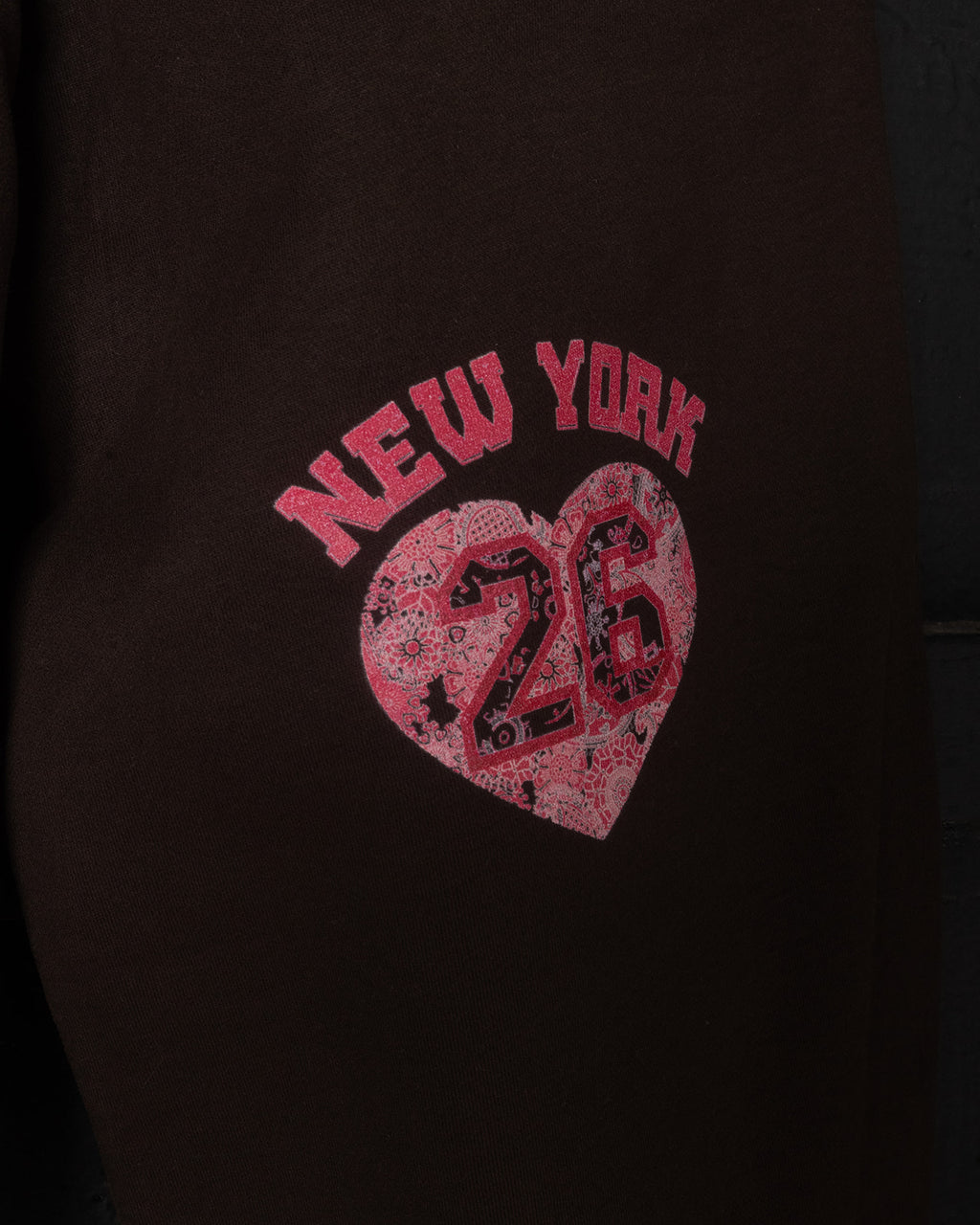 Brown sweatpants with a pink 'New York 26' heart design on a dark background