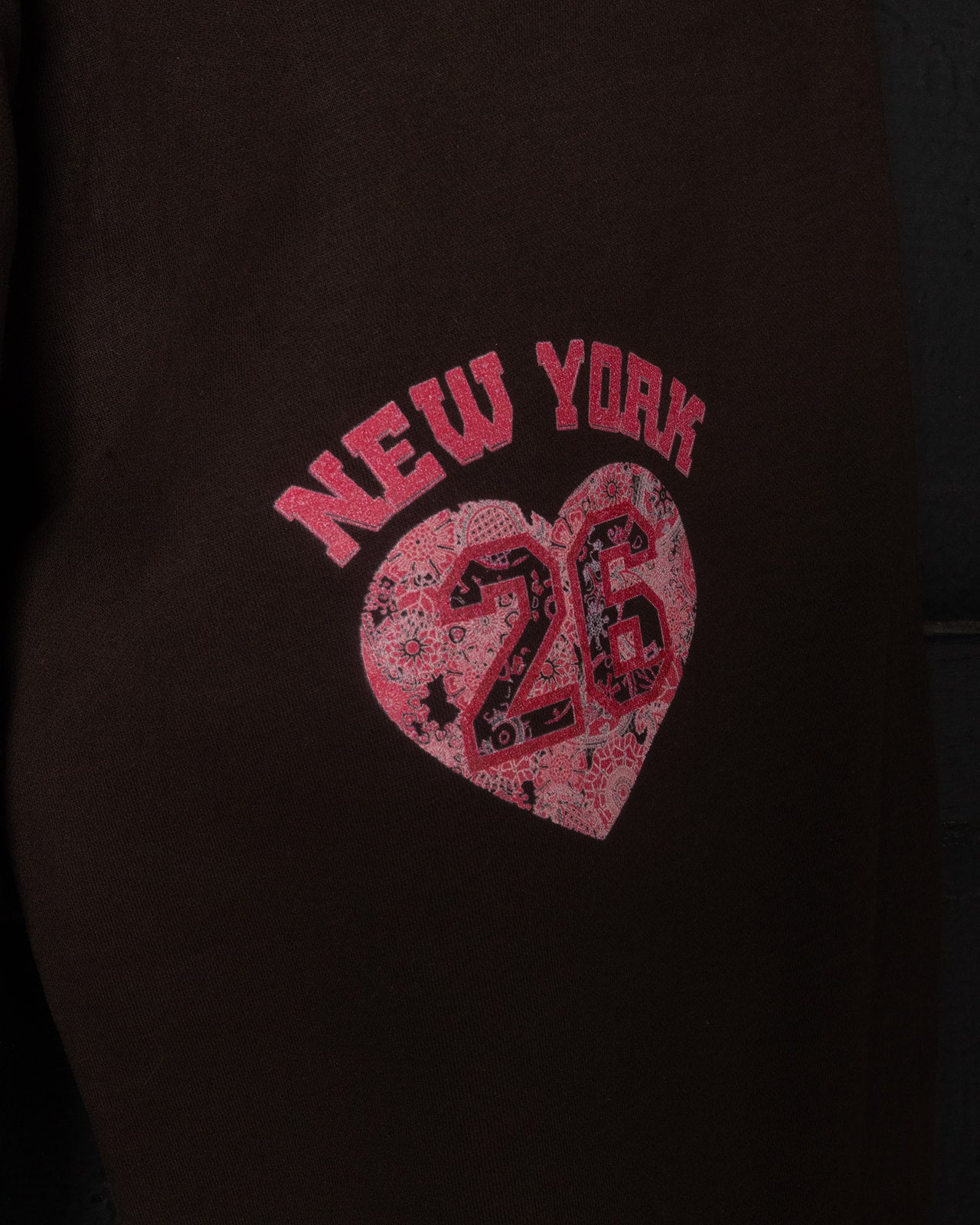 Brown sweatpants with a pink 'New York 26' heart design on a dark background