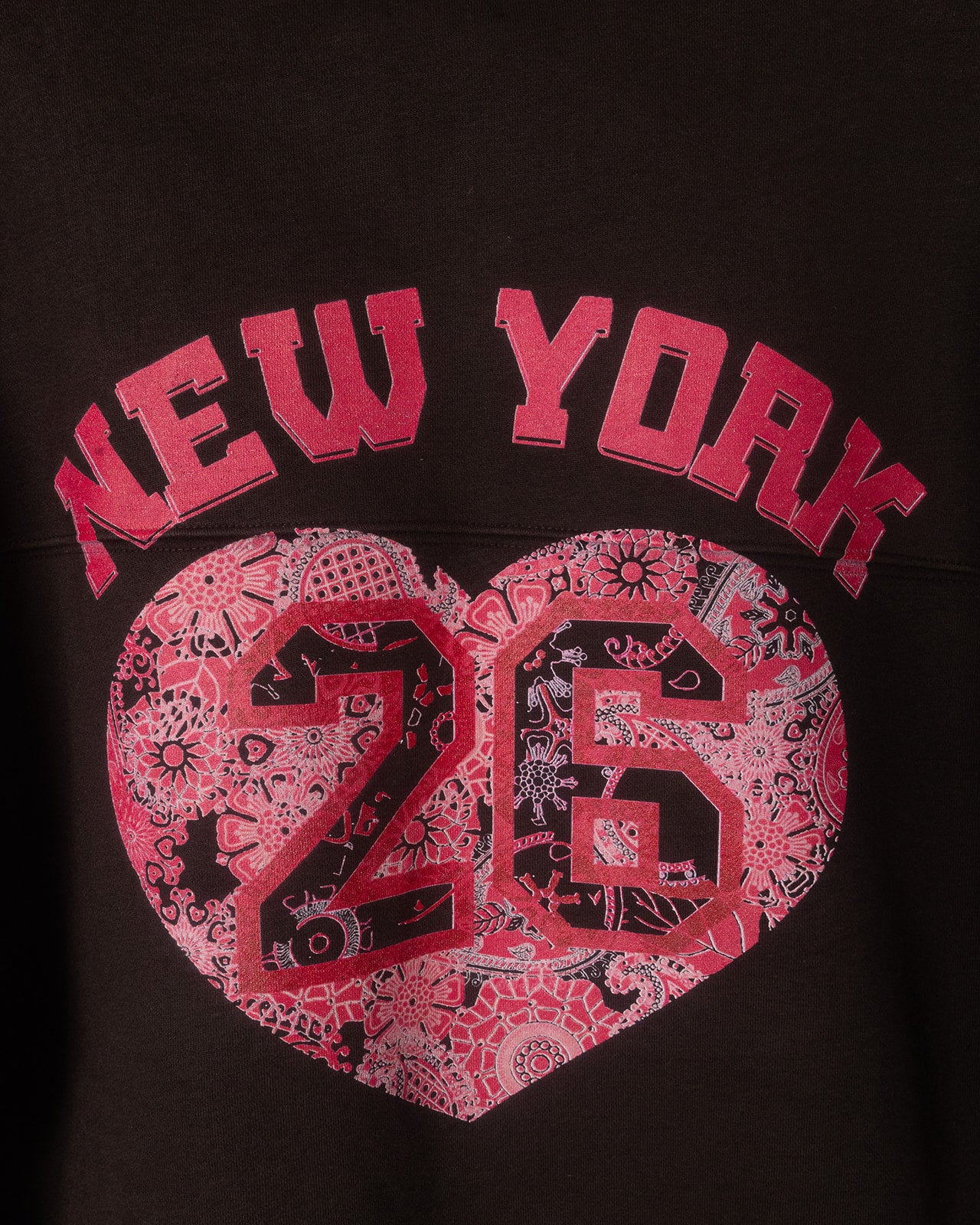 Black sweatshirt with pink 'New York 26' design on a dark background