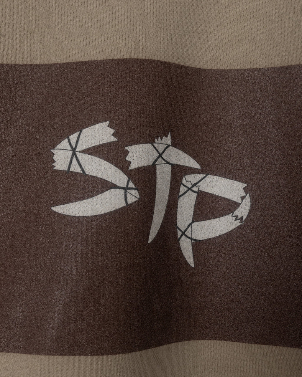 Close-up of a STP logo on a brown fabric surface
