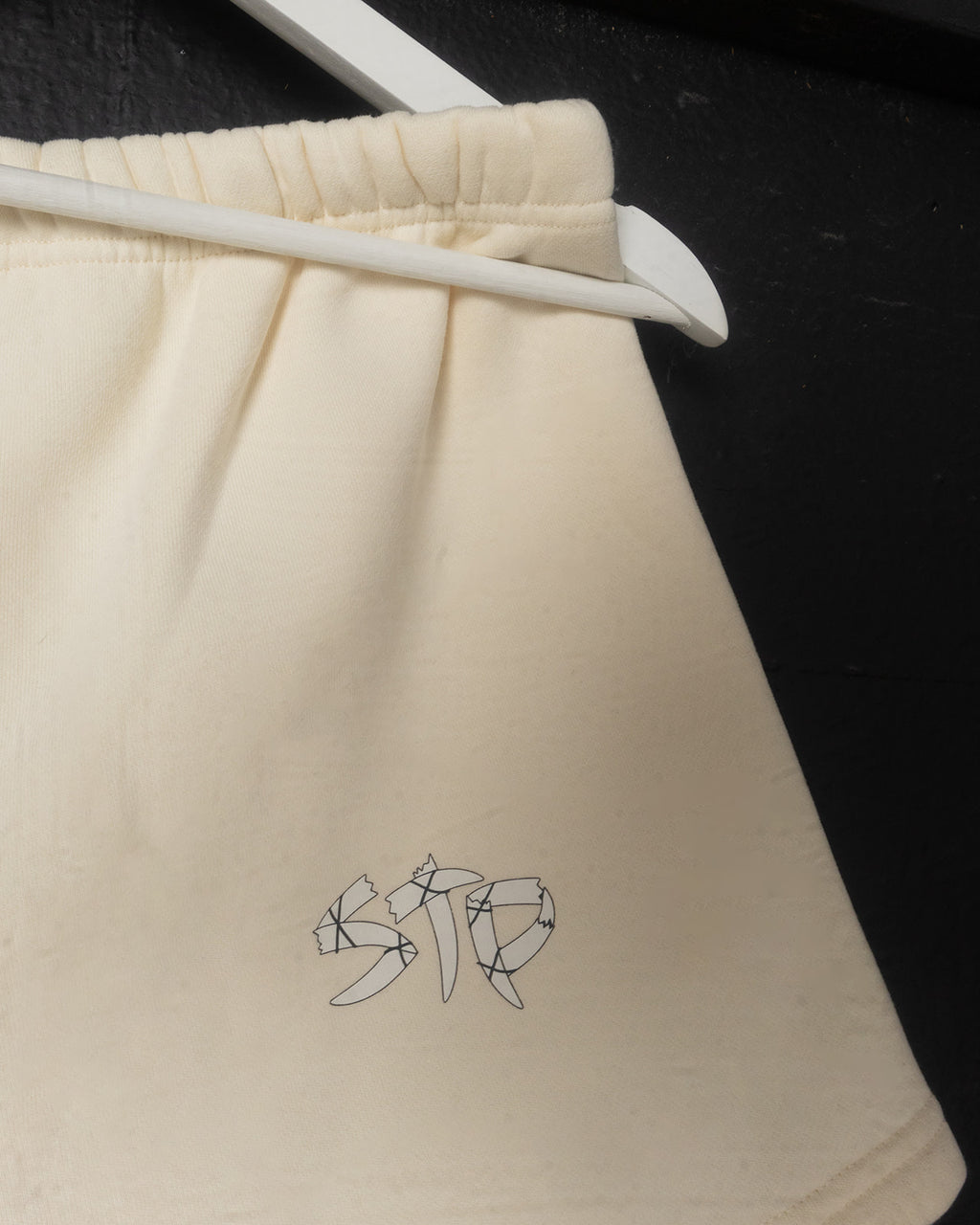 Beige shorts with a geometric logo on a black background
