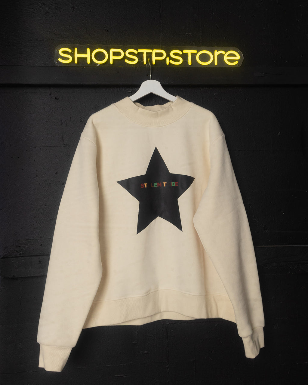 Beige sweatshirt with a black star design on a dark background with 'SHOPSTP.STORE' branding.