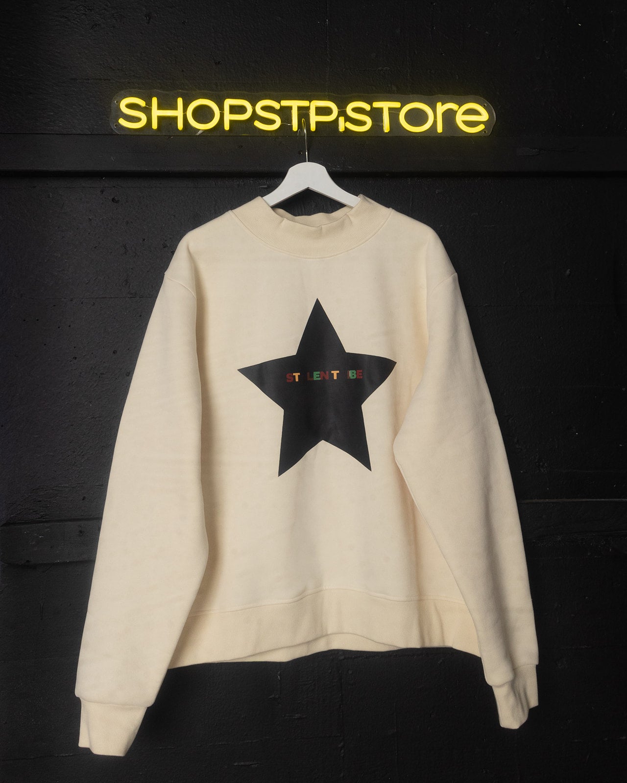 Beige sweatshirt with a black star design on a dark background with 'SHOPSTP.STORE' branding.