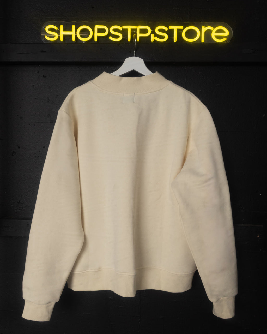 Beige sweatshirt on a hanger with 'SHOPSTP STORE' logo above on a dark background