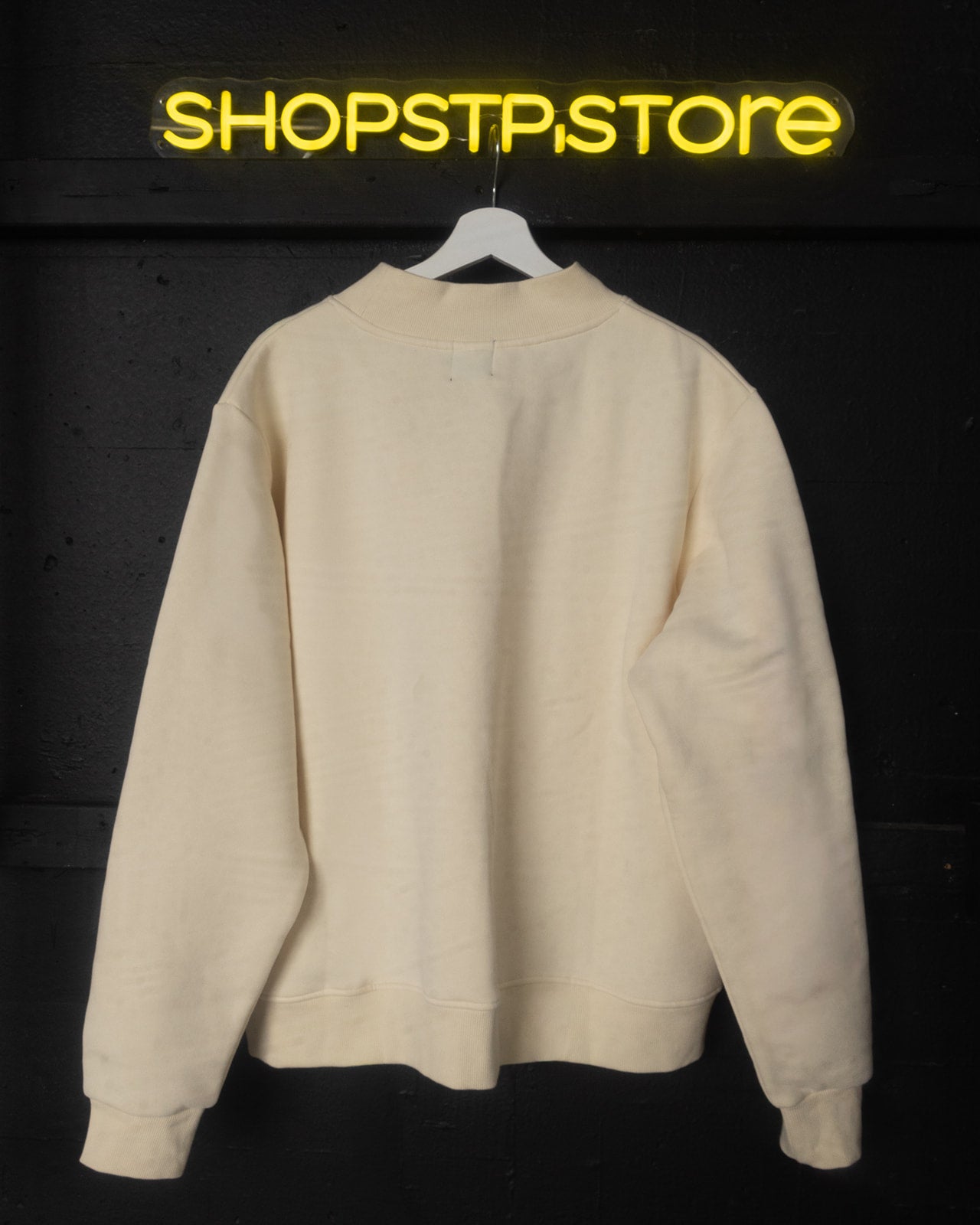 Beige sweatshirt on a hanger with 'SHOPSTP STORE' logo above on a dark background