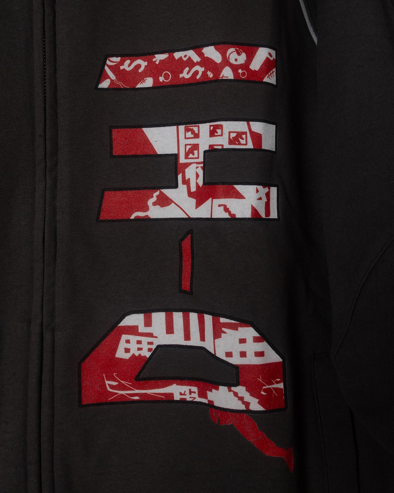 Gray jacket with red and white patterned text design on a dark background