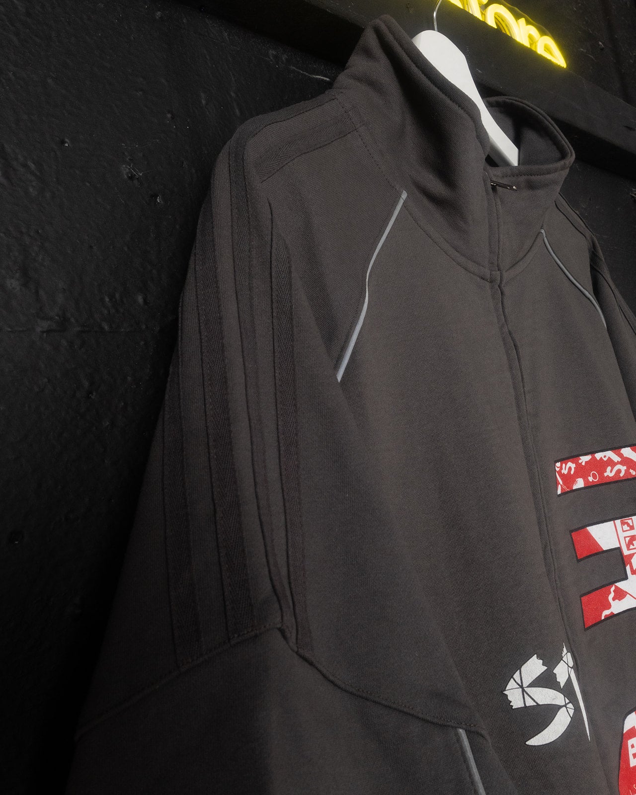 Gray jacket with red and white logo on a black background