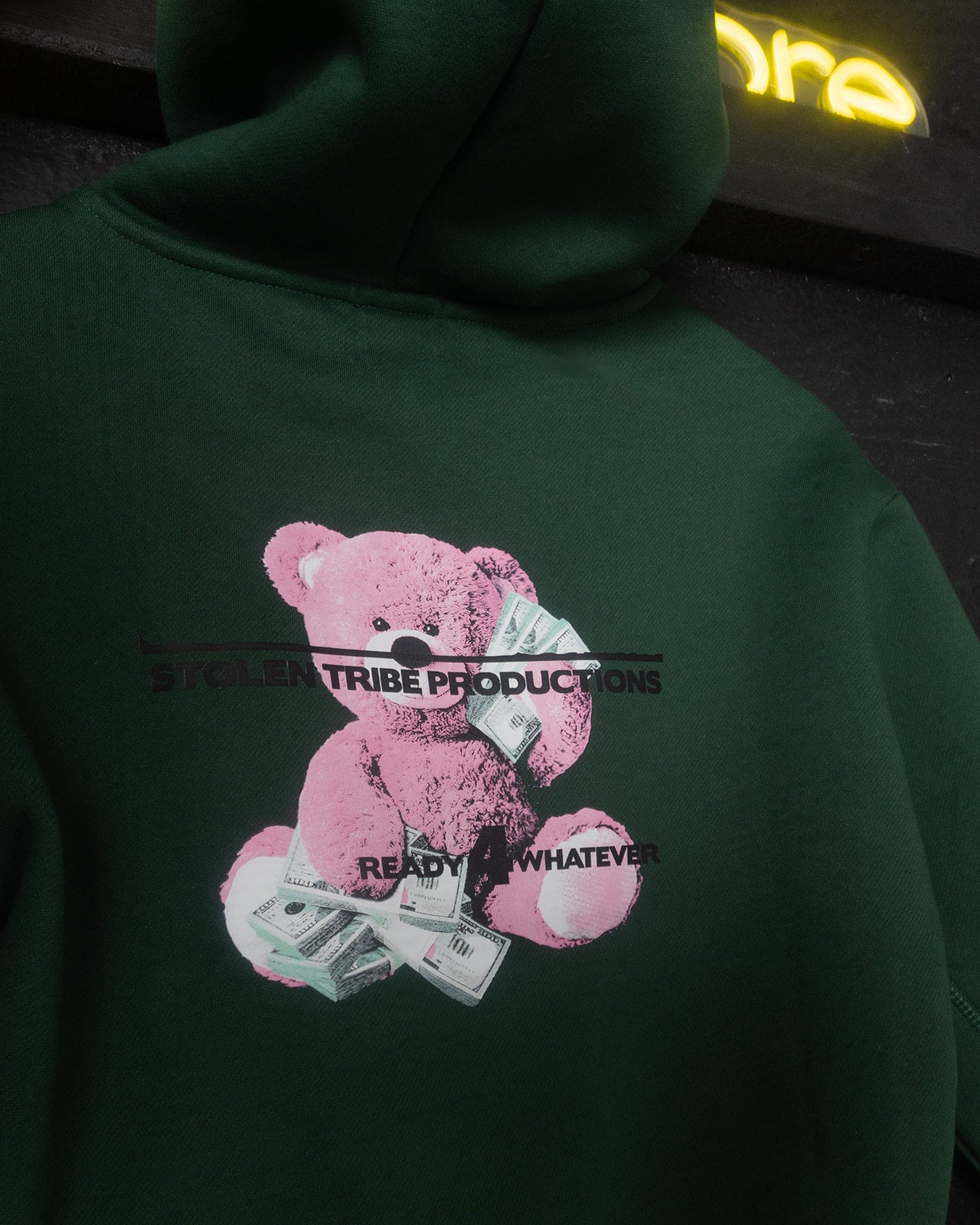 Green hoodie with a pink teddy bear graphic and text on a dark background