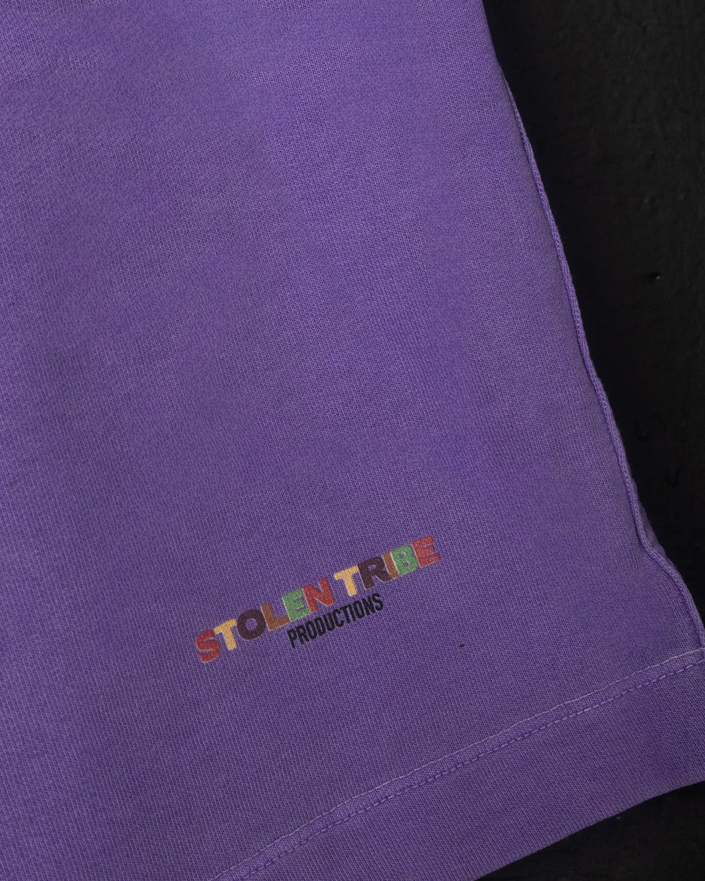 Close-up of a purple garment with 'STOLEN TRIBE PRODUCTIONS' embroidered on it.
