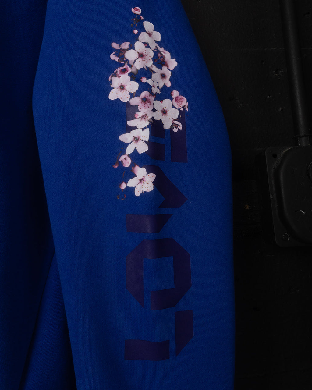 Blue hoodie with cherry blossom design on a dark background