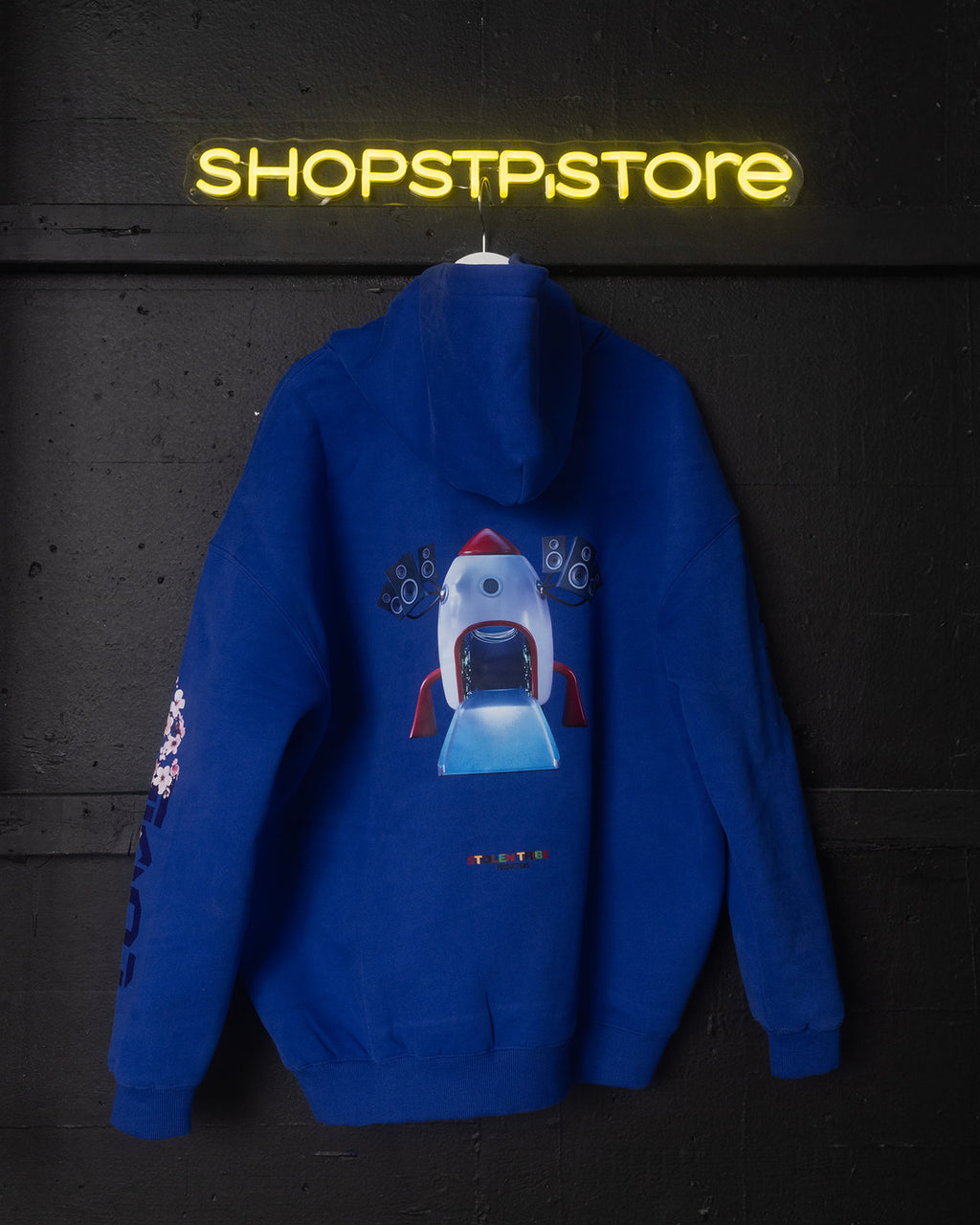 Blue hoodie with a robot design on a dark background with 'SHOPSTP STORE' neon sign.
