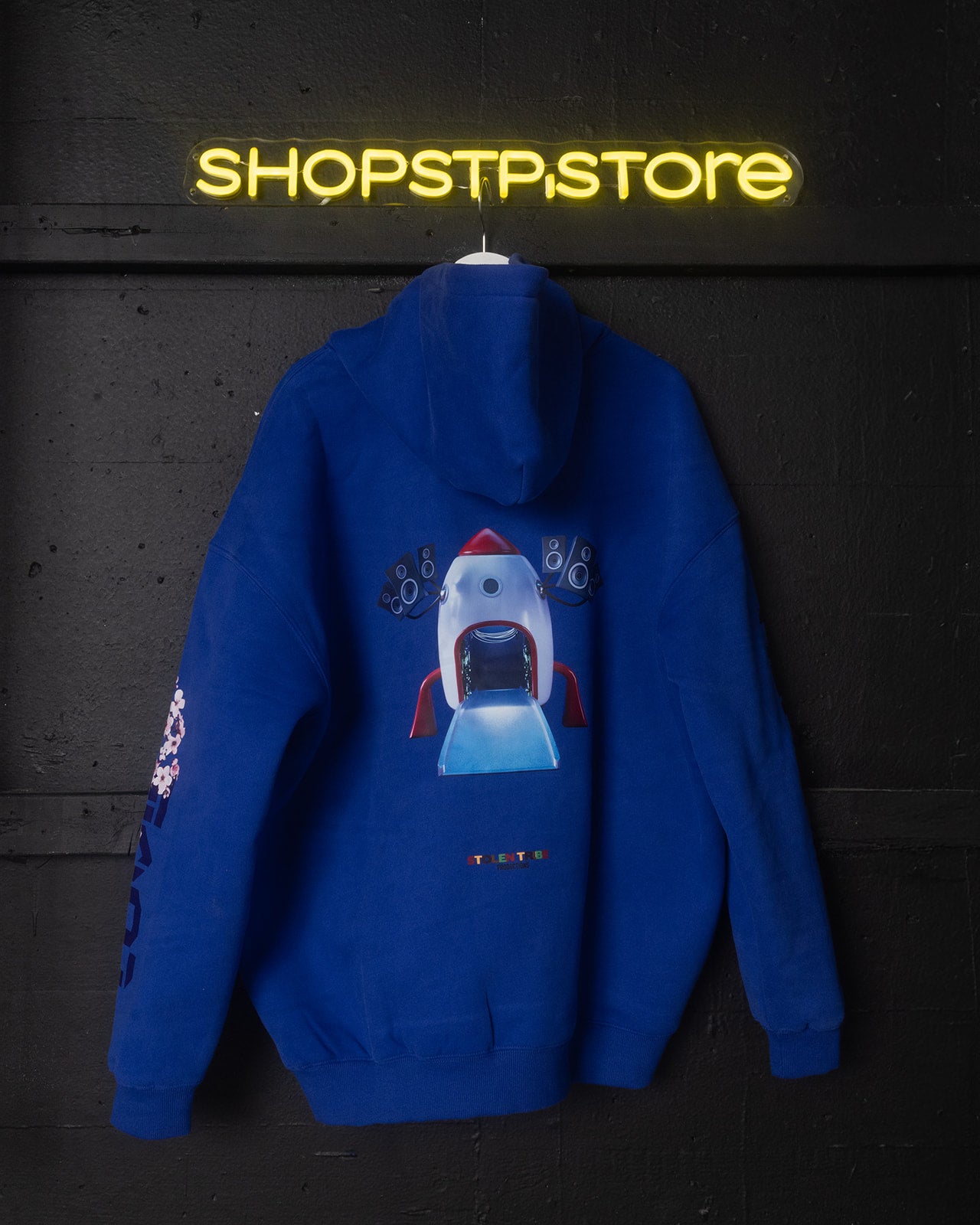 Blue hoodie with a robot design on a dark background with 'SHOPSTP STORE' neon sign.