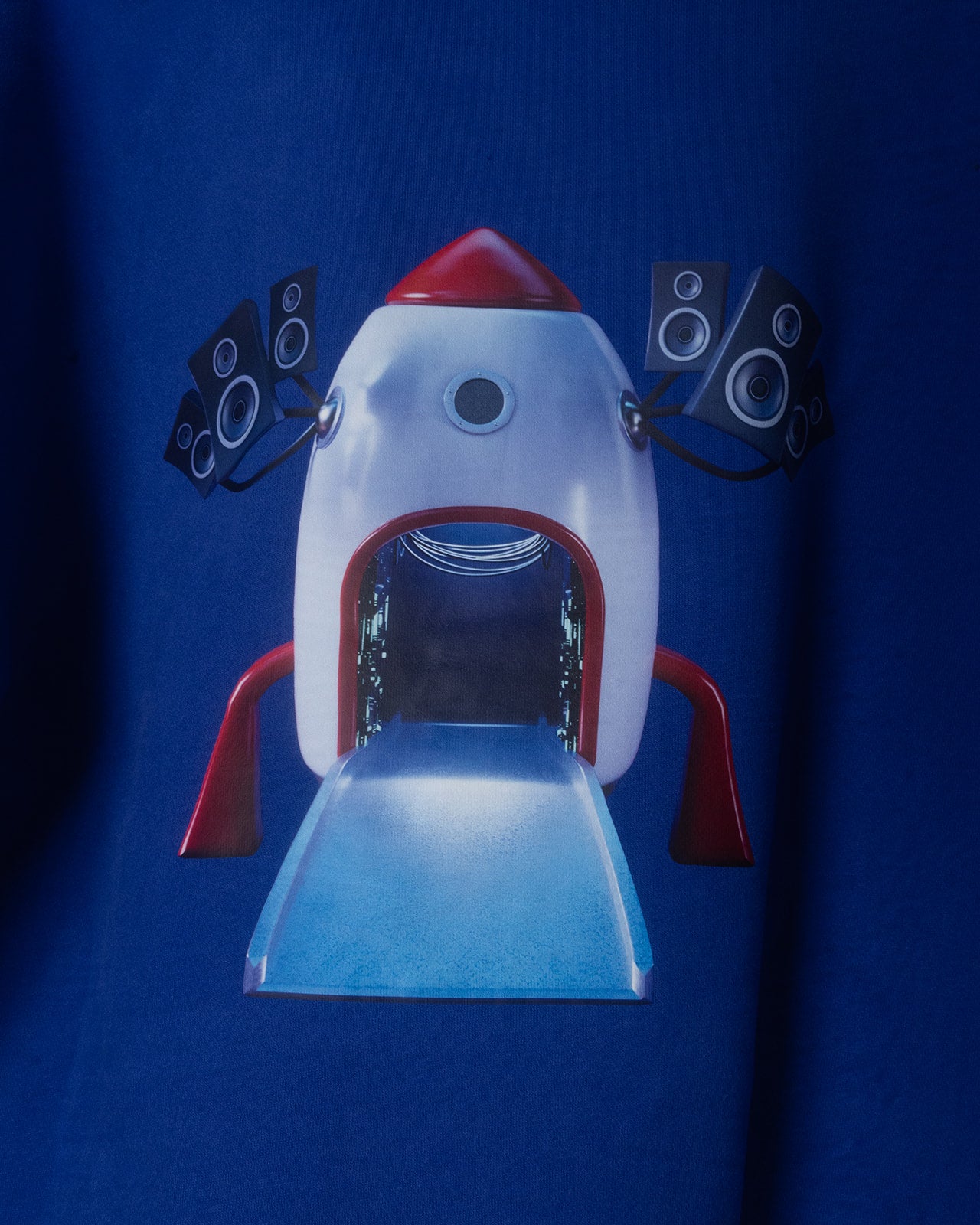 Toy rocket ship with speakers on a blue hoodie and black background