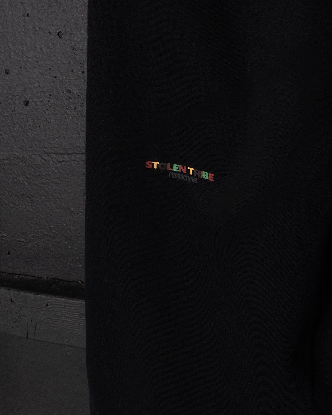 Black sweatpants with colorful 'STOLEN TRIBE' logo on a dark background