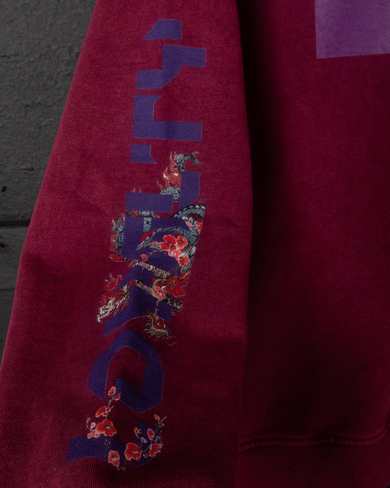 Red sweatshirt with a colorful graphic design on a dark background