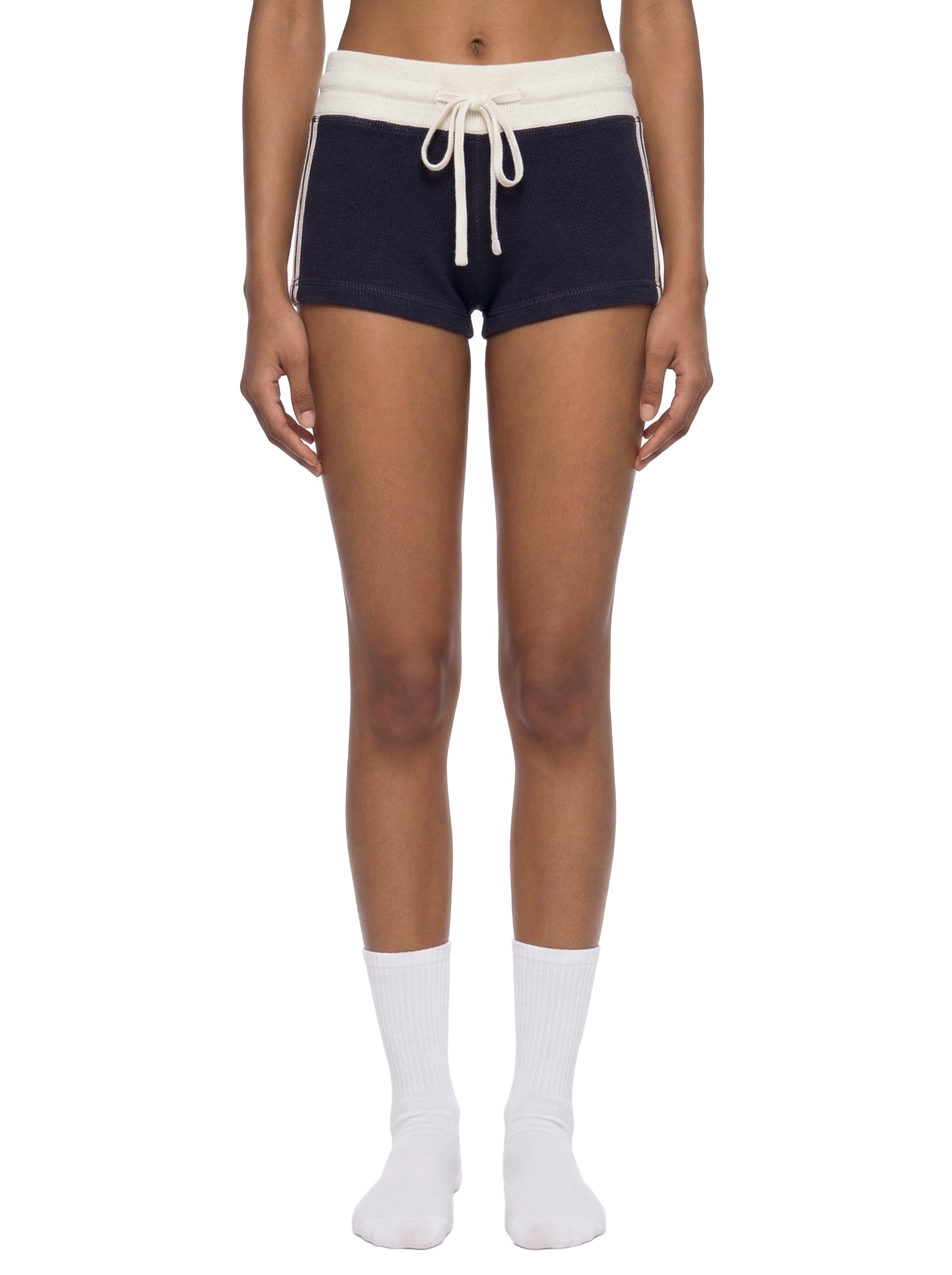 Person wearing navy shorts with white drawstring and trim on a white background