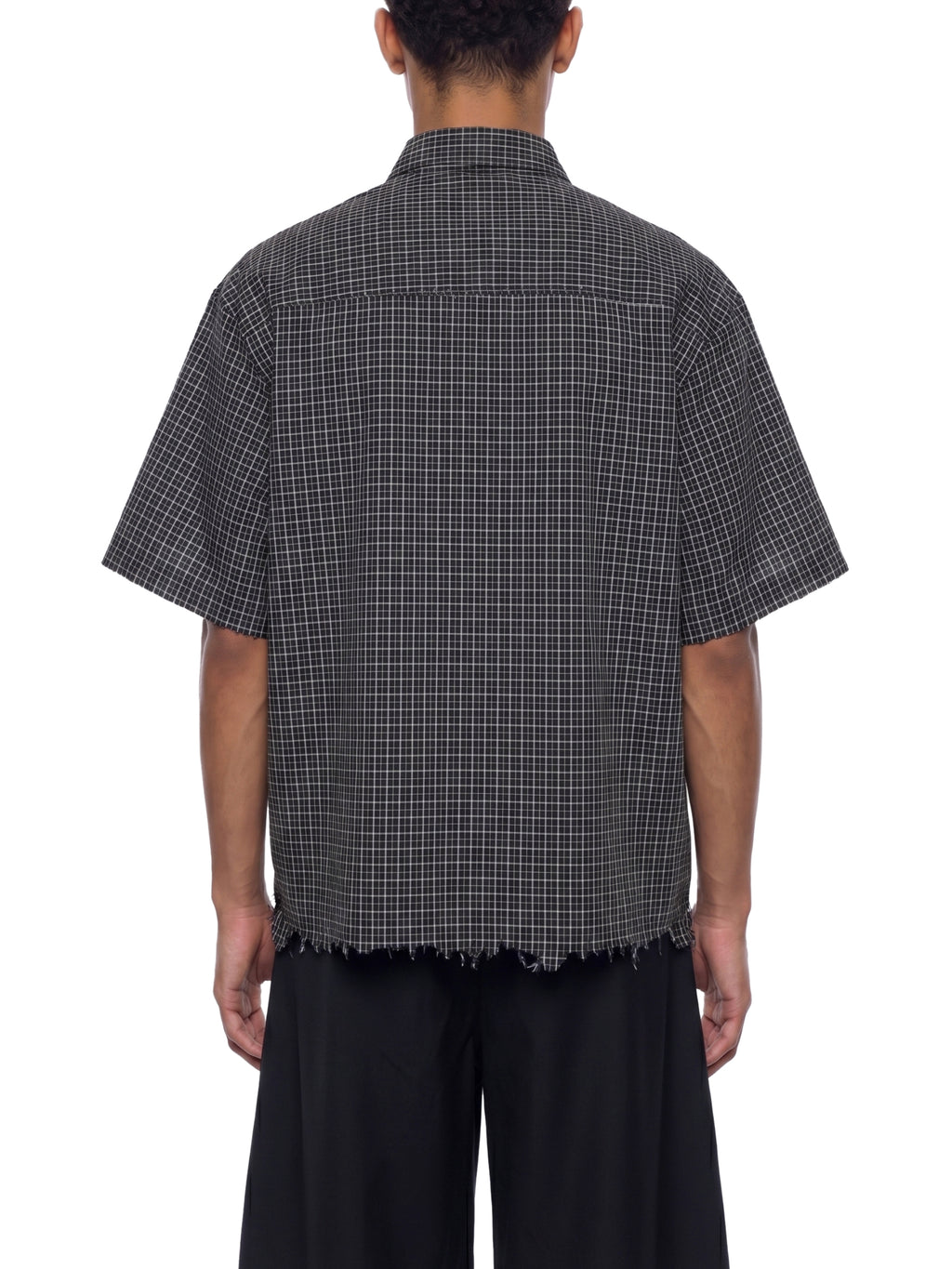 Person wearing a black and white checkered shirt with short sleeves on a white background
