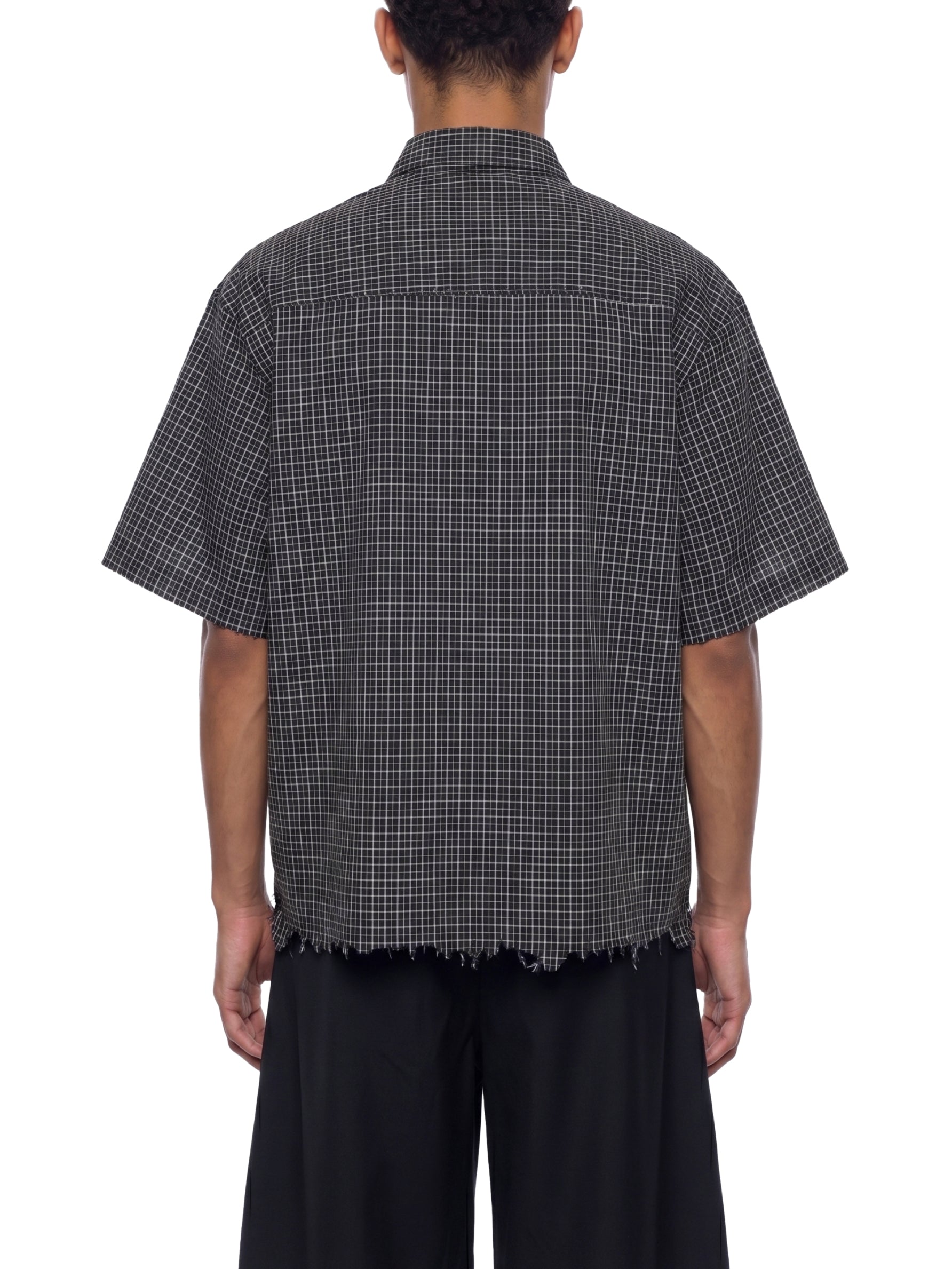 Person wearing a black and white checkered shirt with short sleeves on a white background