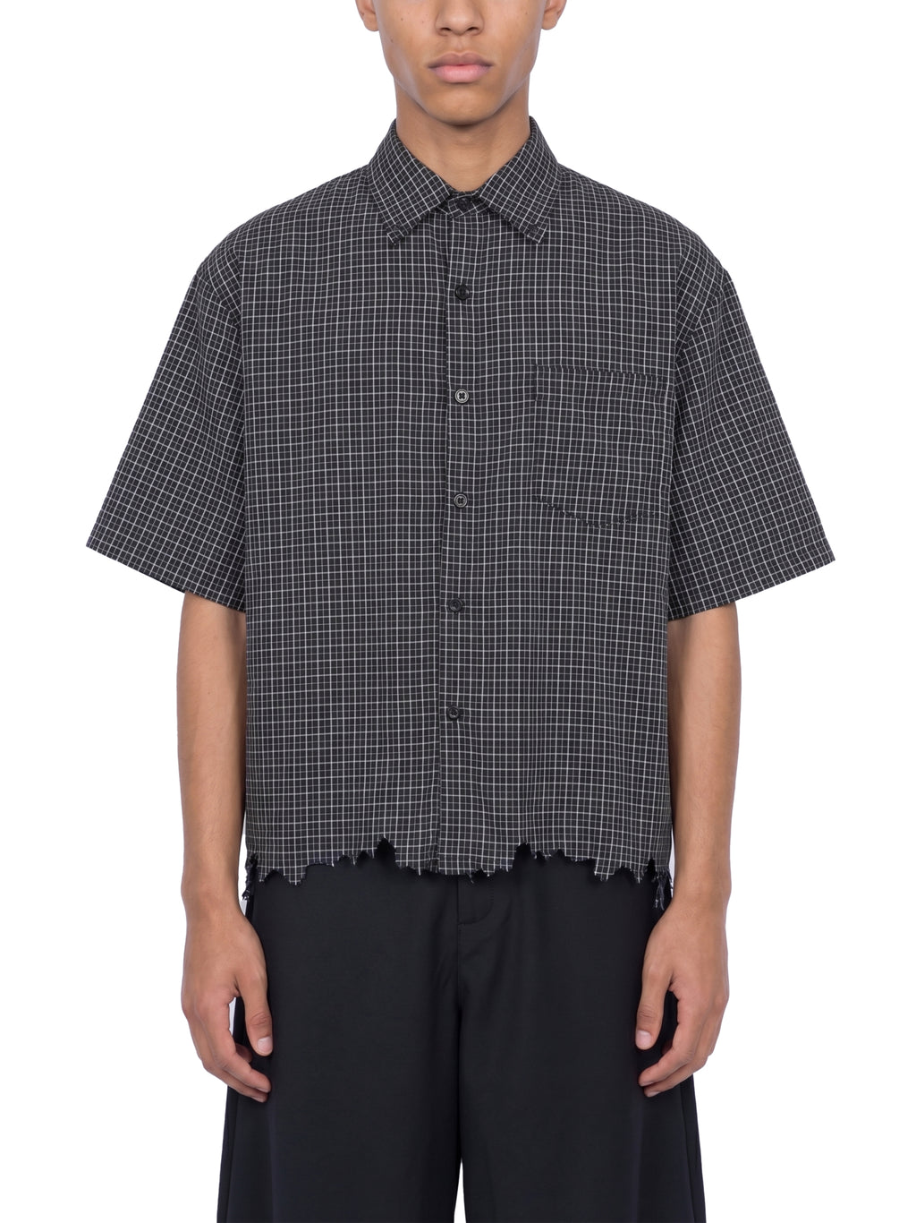 Person wearing a black and white checkered shirt with short sleeves on a white background