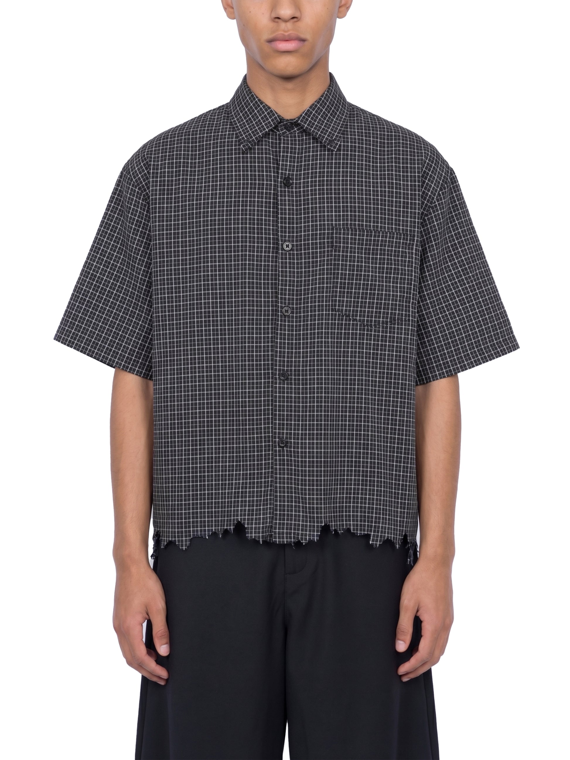 Person wearing a black and white checkered shirt with short sleeves on a white background
