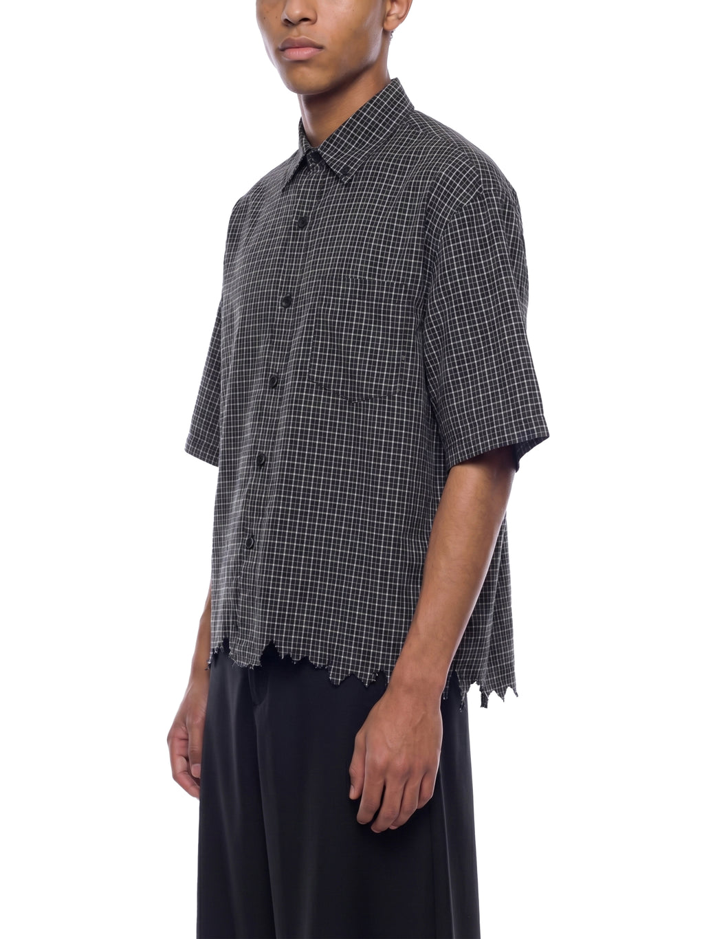 Person wearing a black and white checkered shirt with short sleeves on a white background