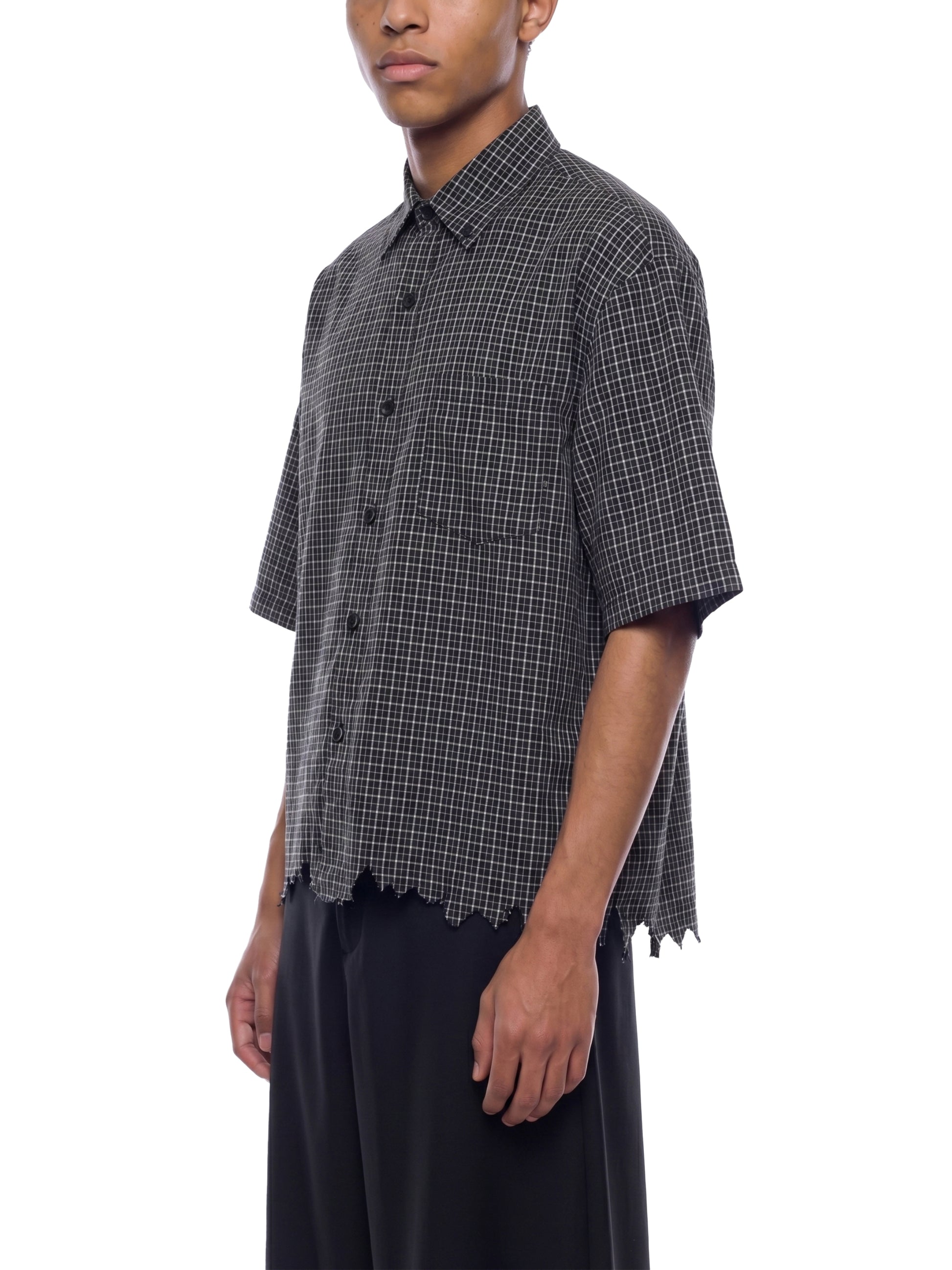 Person wearing a black and white checkered shirt with short sleeves on a white background