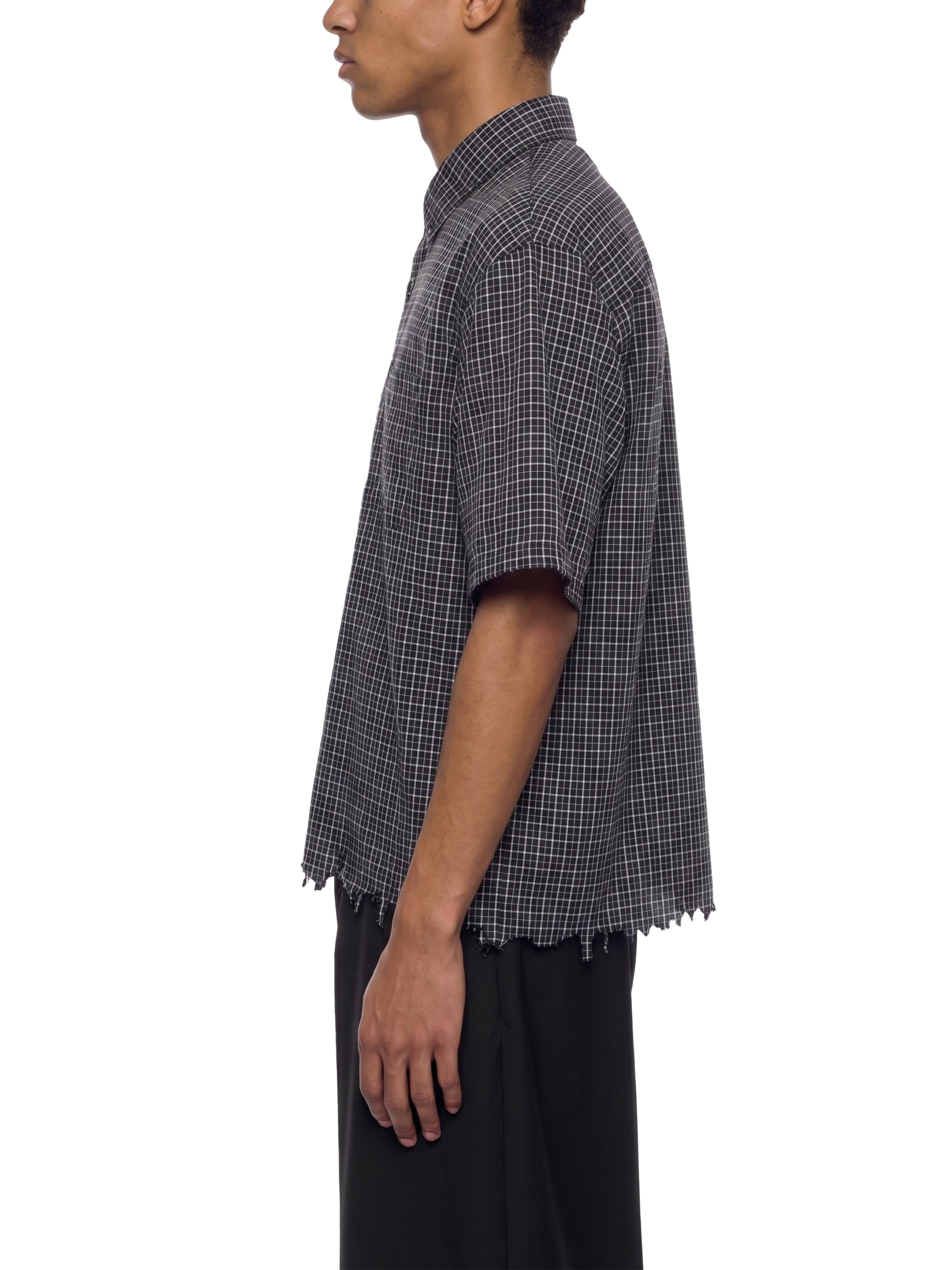 Person wearing a checkered shirt with short sleeves on a white background