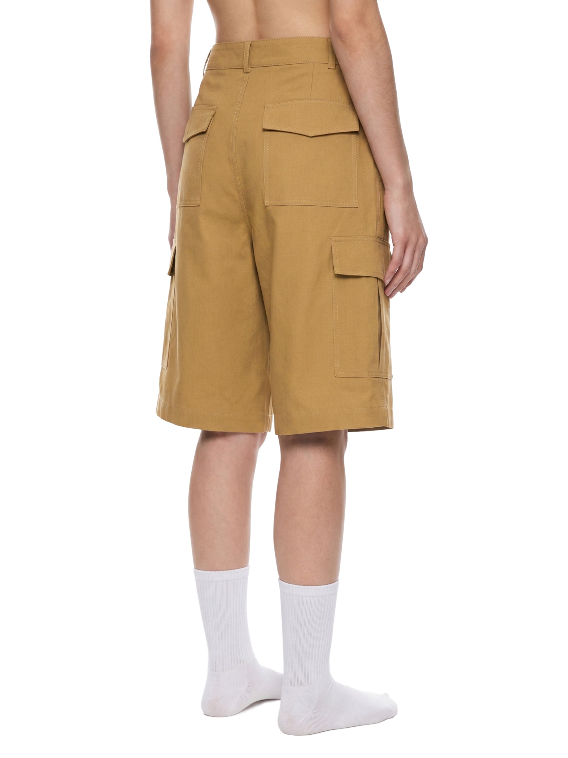 Person wearing tan cargo shorts on a white background