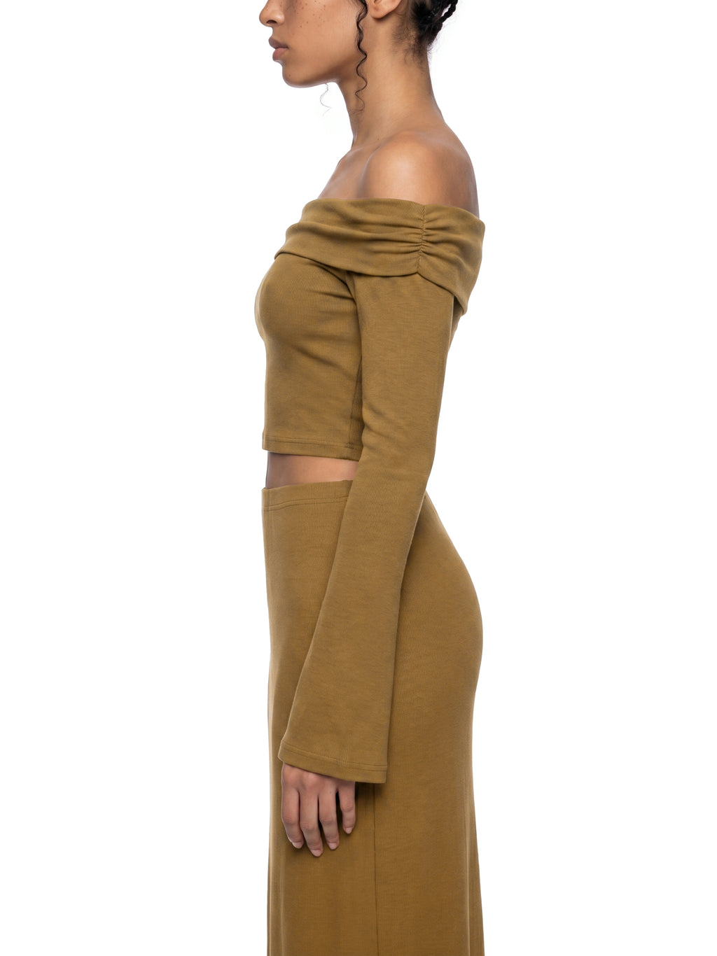 Side view of a person wearing a mustard yellow off-shoulder dress on a white background