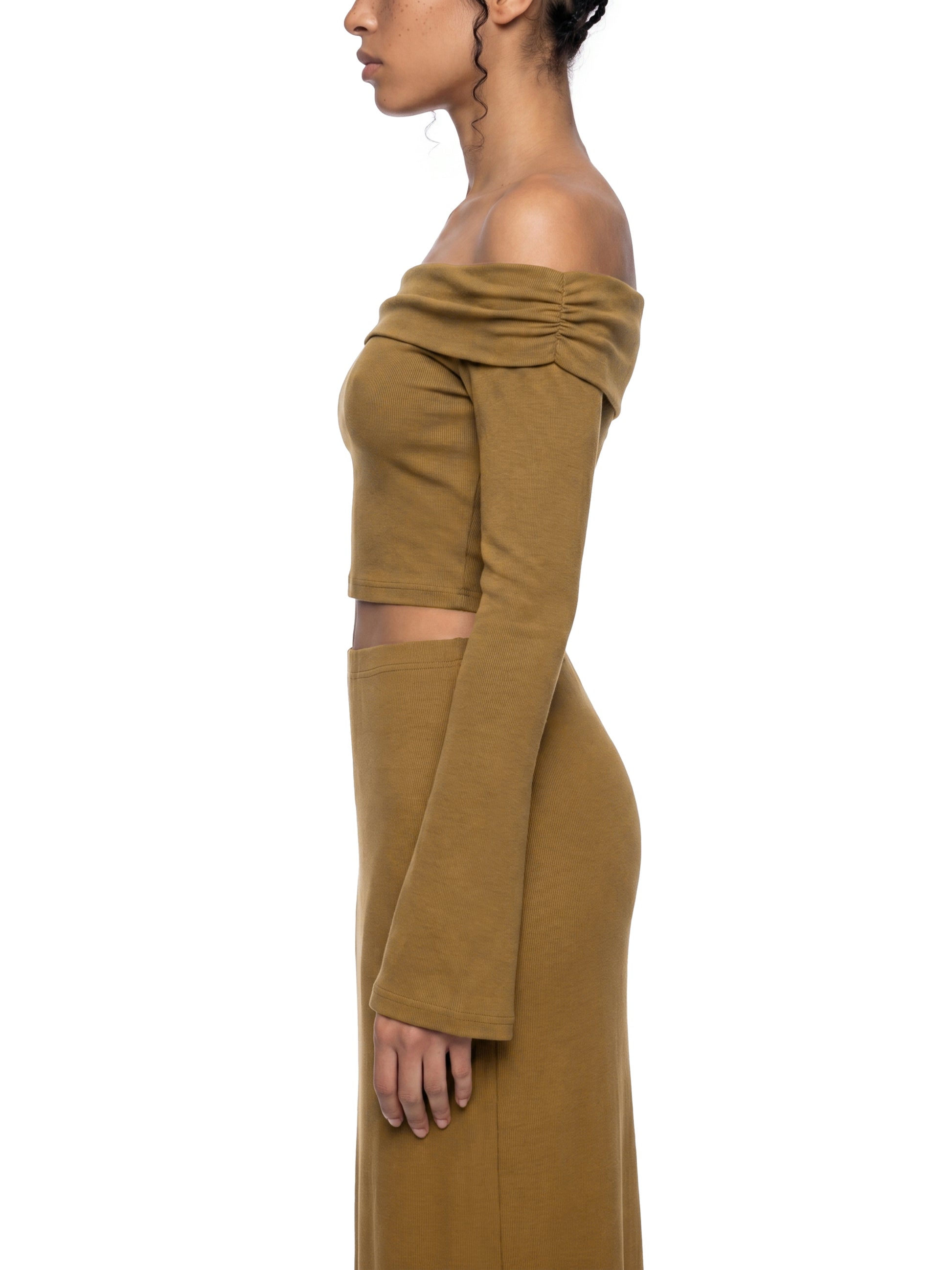 Side view of a person wearing a mustard yellow off-shoulder dress on a white background