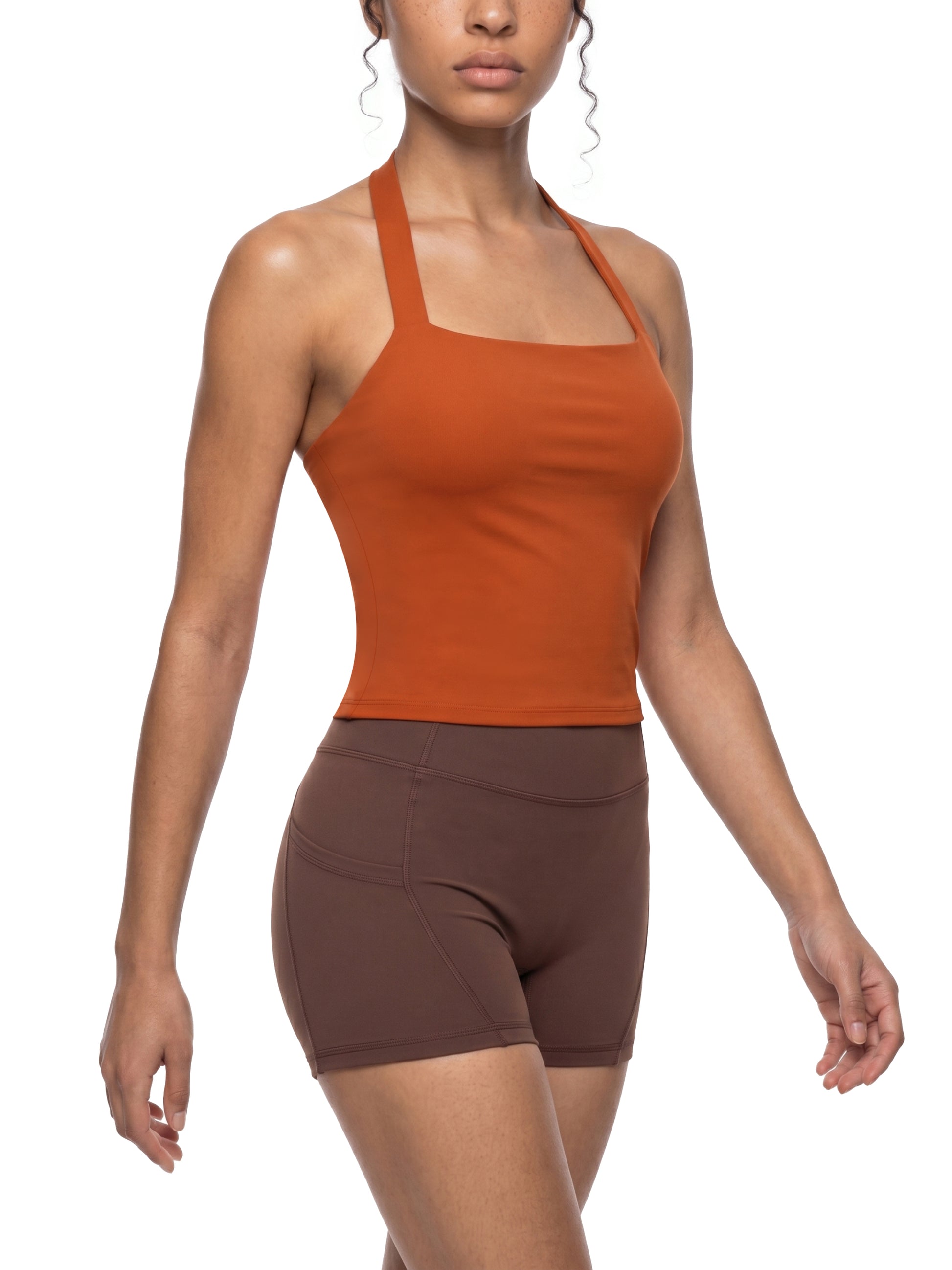 Woman wearing an orange tank top and brown shorts on a white background