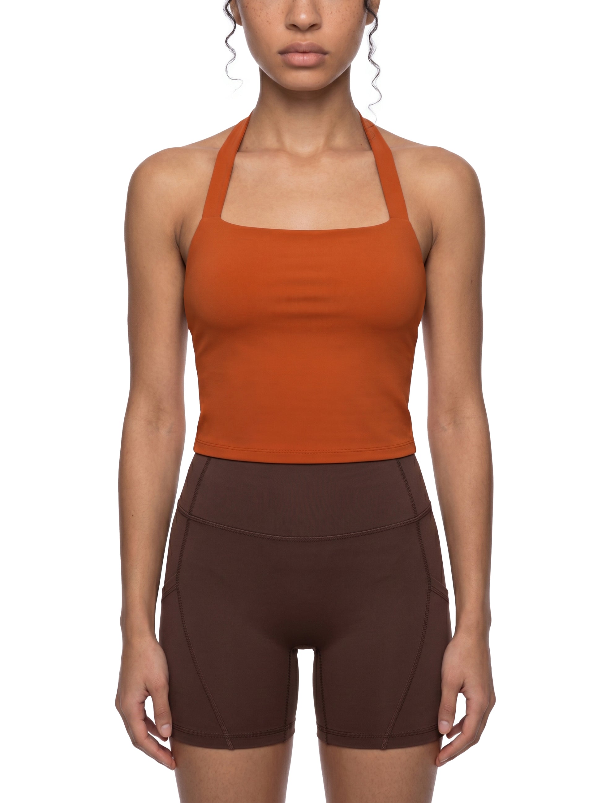Person wearing an orange tank top and brown shorts on a white background