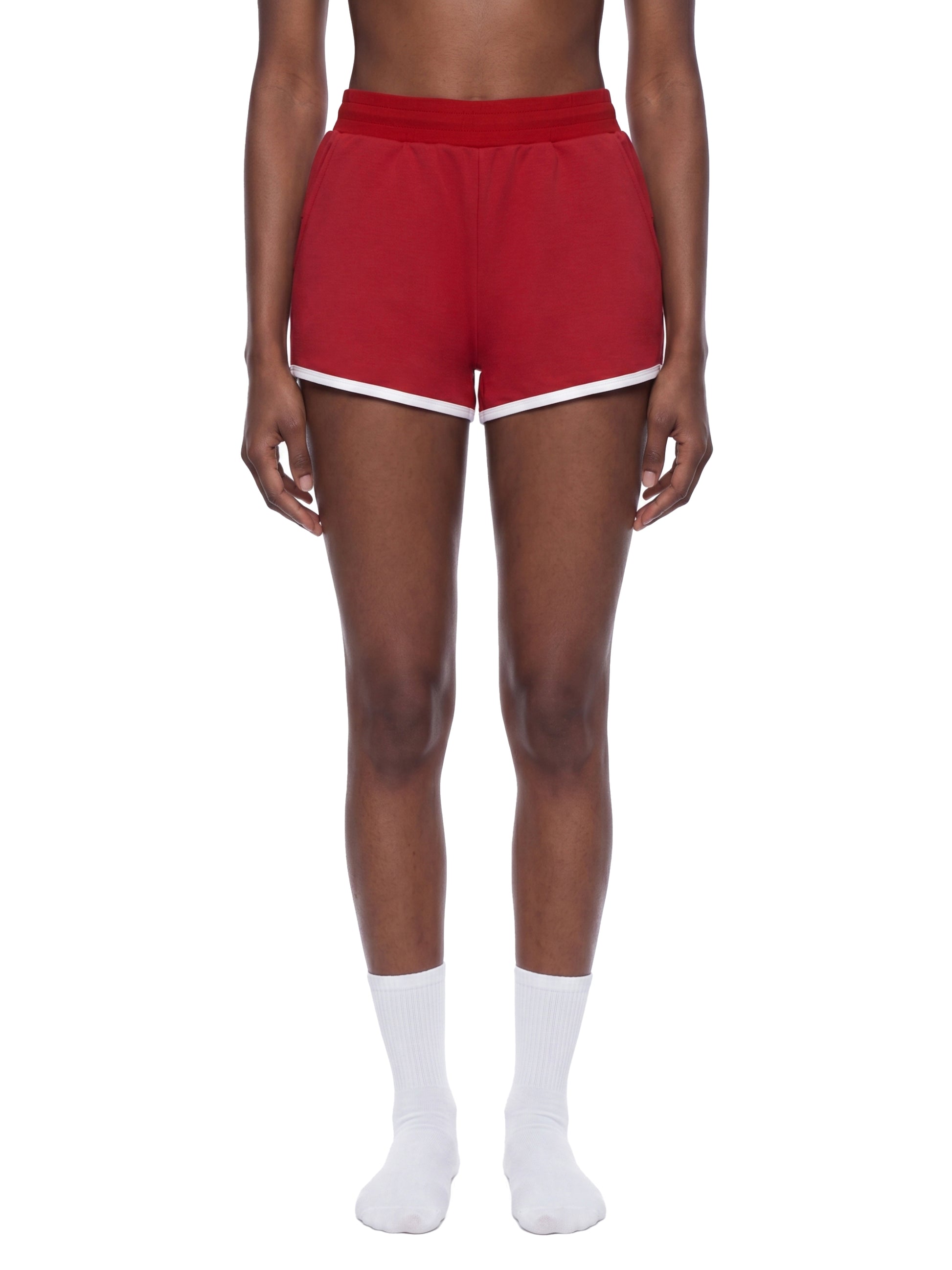 Red shorts with white trim worn by a person on a white background