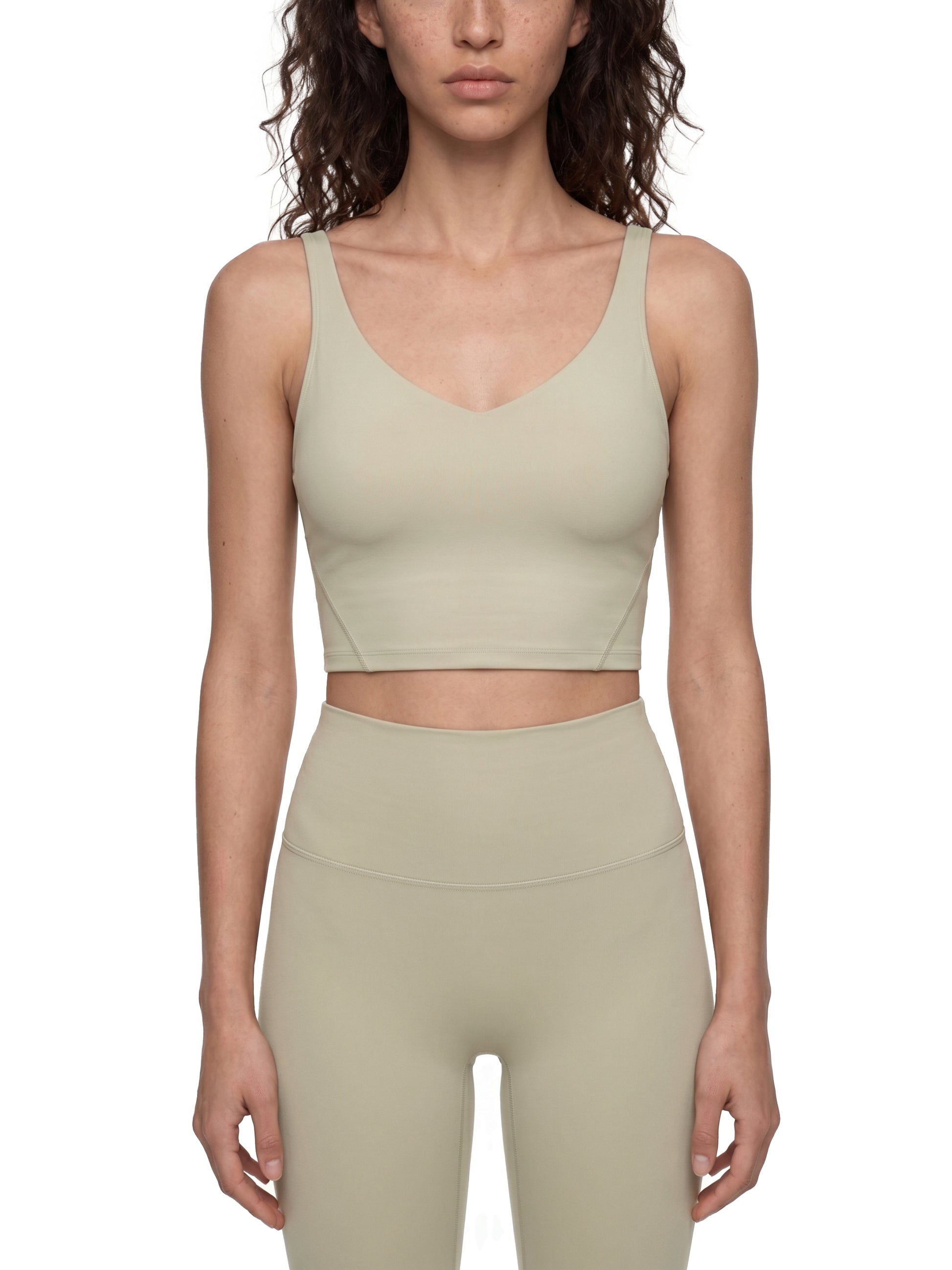 Woman wearing a beige sports bra and leggings set on a white background