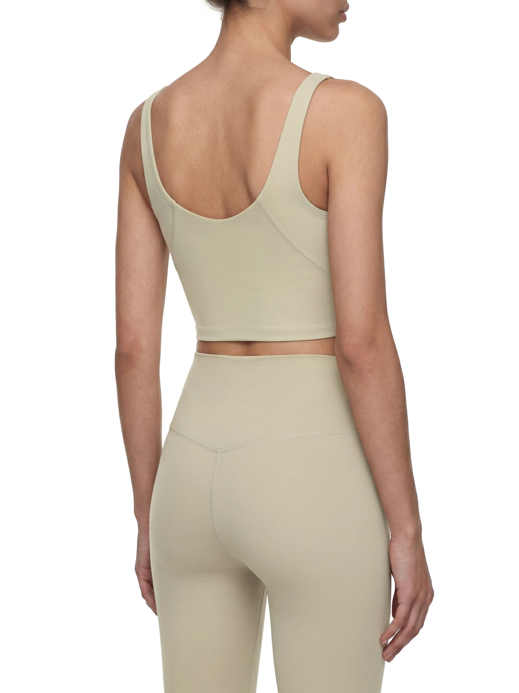 Person wearing a beige sports bra and leggings set on a white background