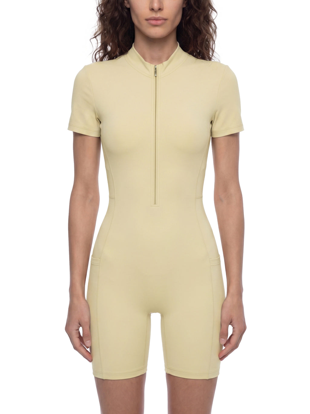 Woman wearing a light yellow bodysuit against a white background
