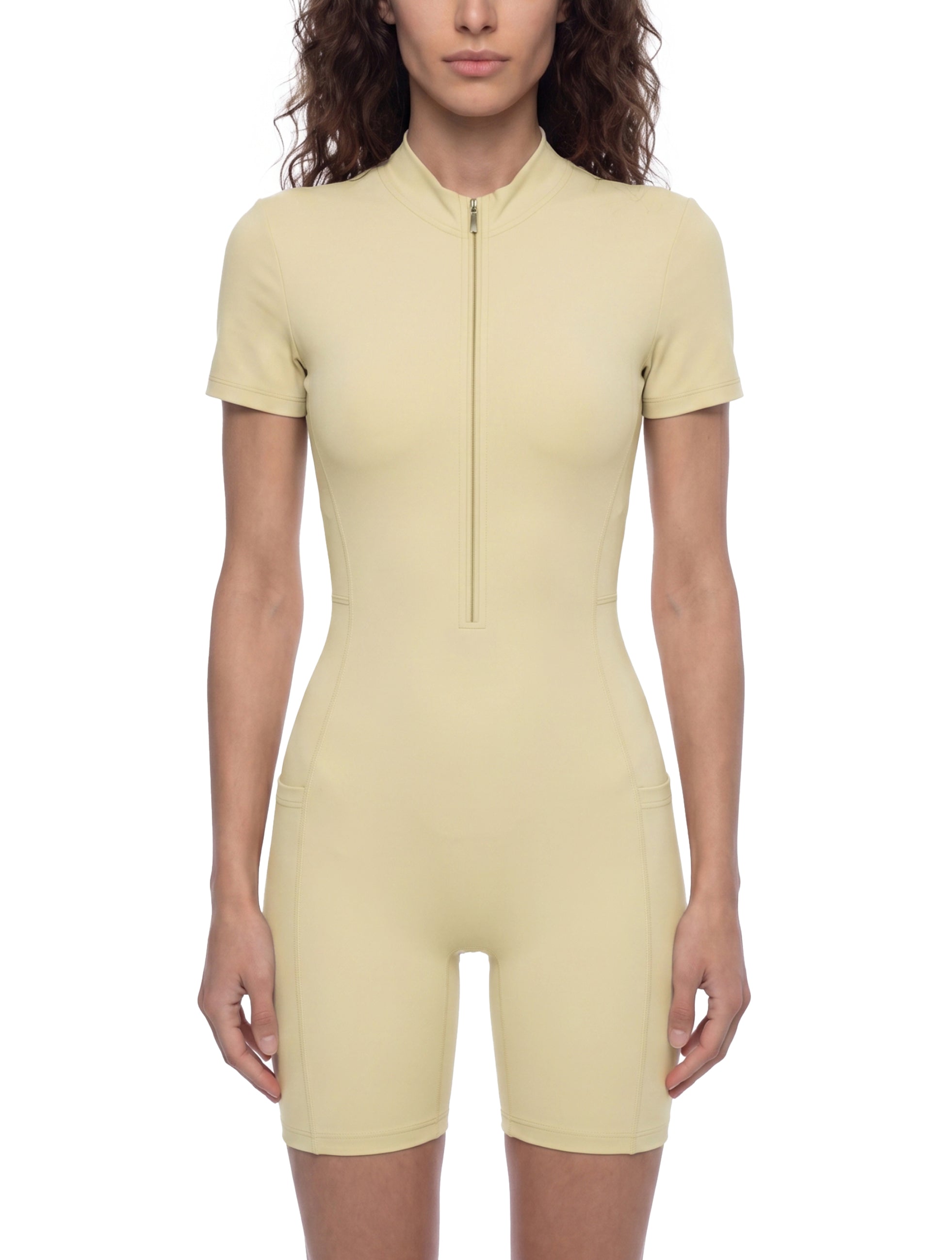 Woman wearing a light yellow bodysuit against a white background