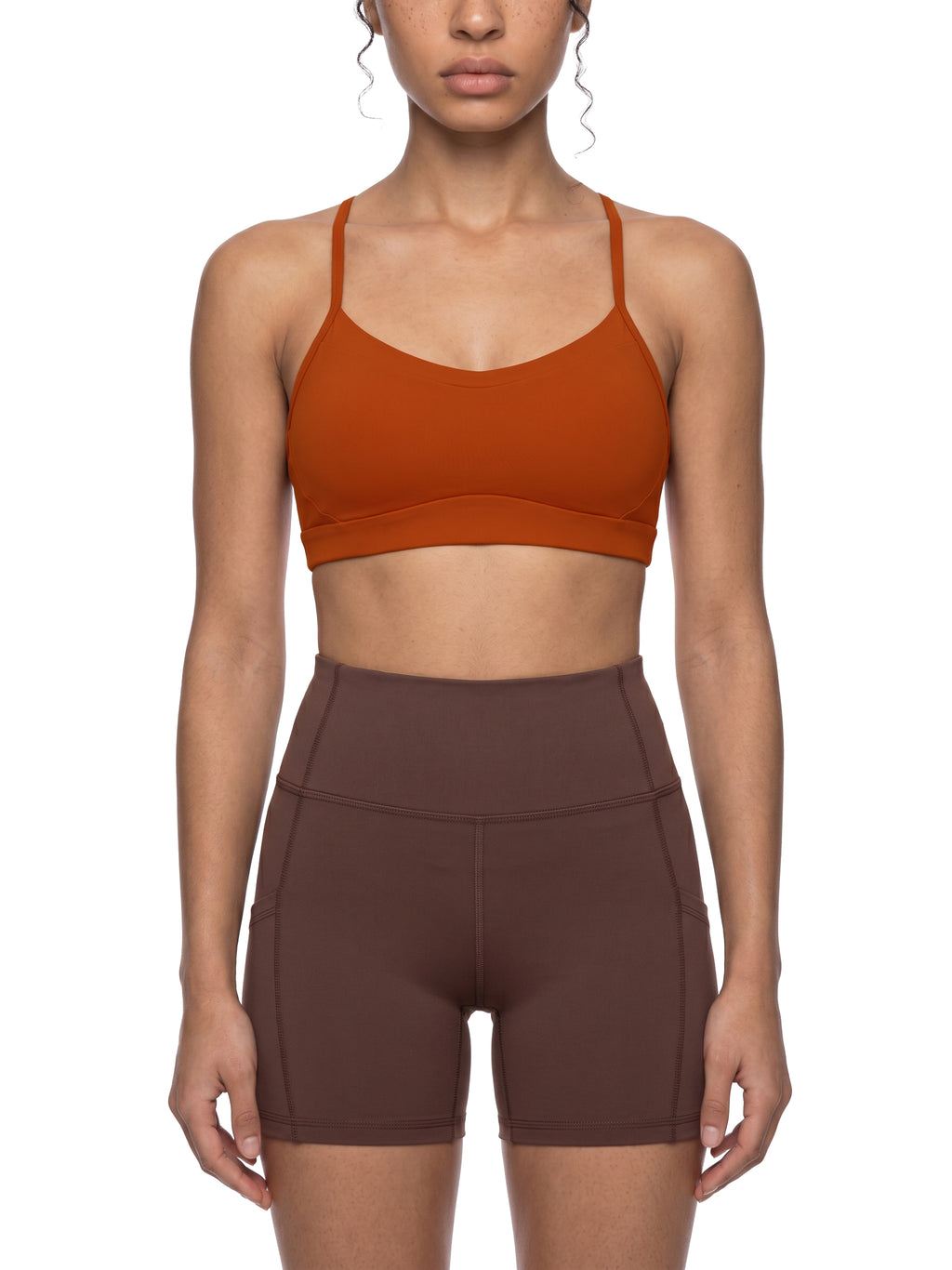 Person wearing a orange sports bra and shorts on a white background